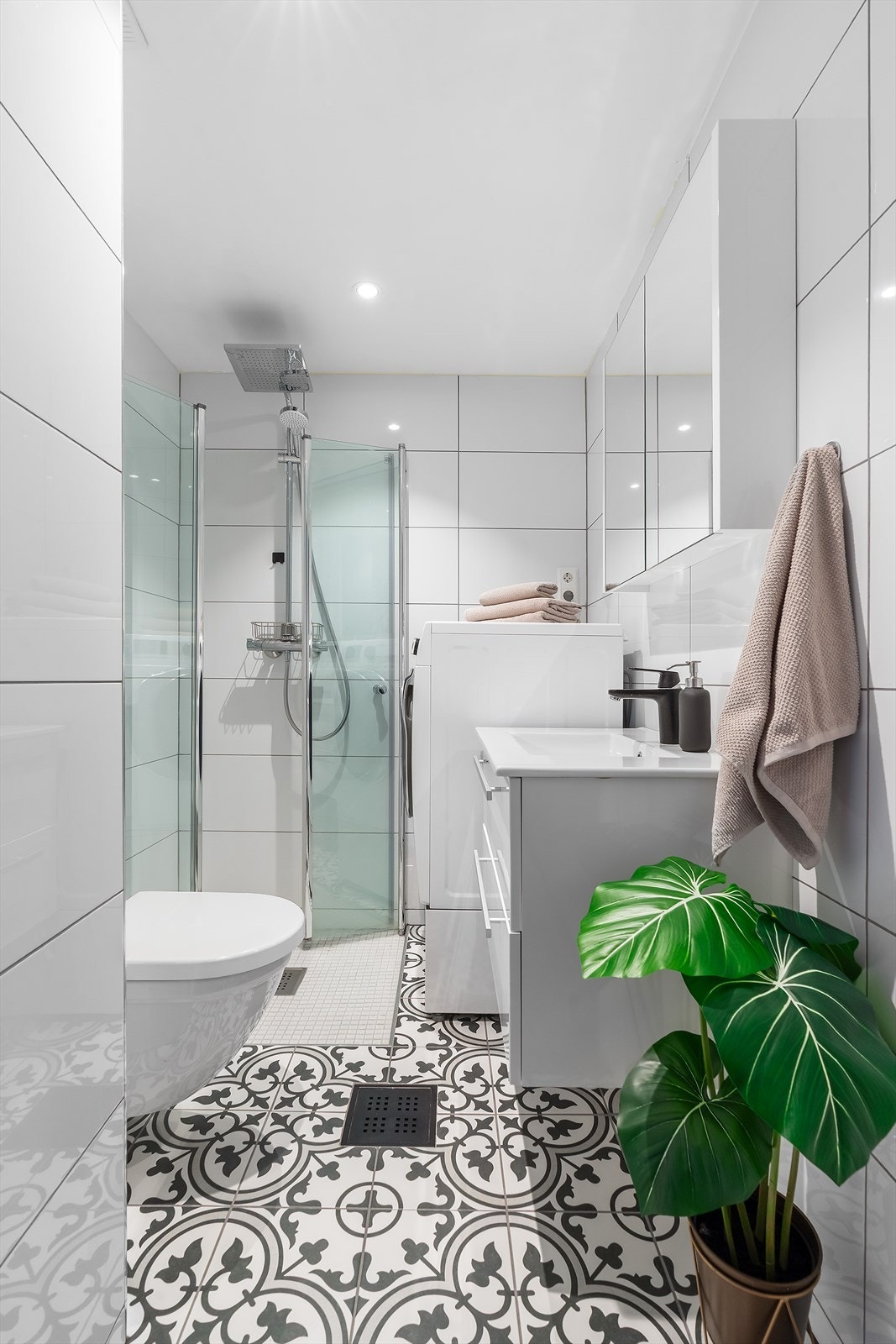 Badet er praktisk innredet med vegghengt toalett, dusj med innfellbare dusjegger i glass, opplegg til vaskemaskin og baderomsinnredning. Galleribilde