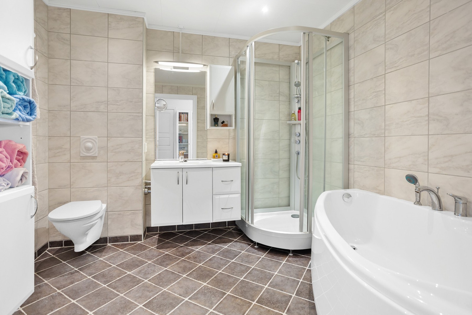 Flislagt bad med varme i gulv. Vegghengt toalett. Badekar og dusjkabinett. Galleribilde