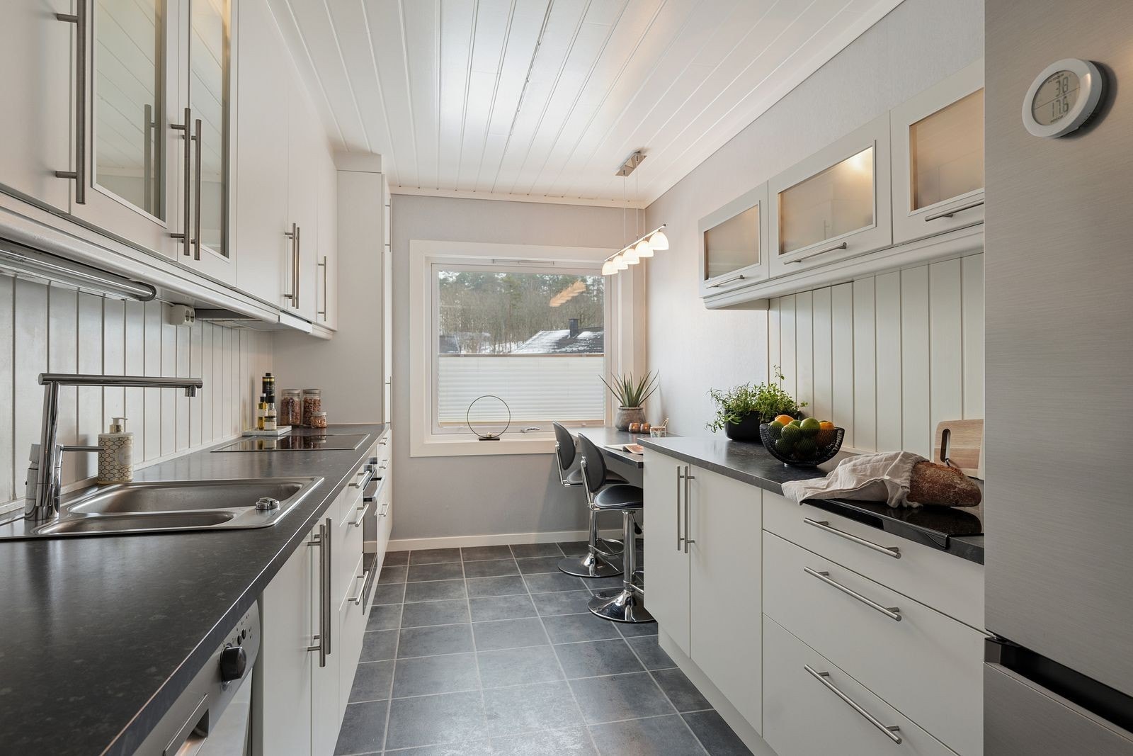 Kjøkken med klassisk innredning i hvitt og benkeplater i laminat. Galleribilde