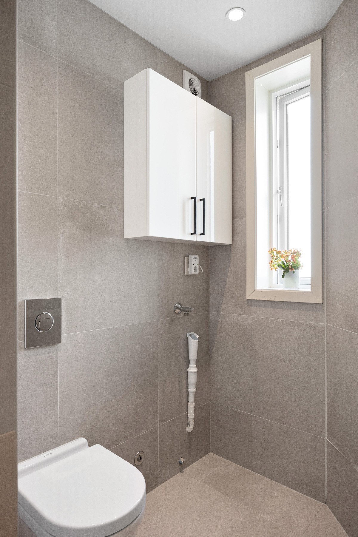 Baderomsinnredningen har hvite fronter og består av en toppmontert servant på en skuffeseksjon, to veggskap og et stort, innfliset speil. Det er også opplegg for vaskemaskin. Galleribilde