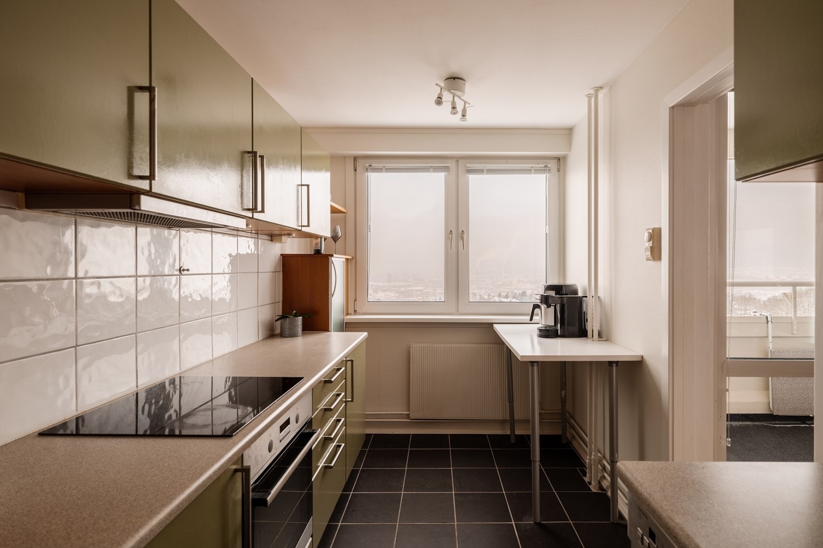 Moderne kjøkkeninnredning med glatte, grønne fronter og fliser over benkeskap. Laminat benkeplate med planlimt kum i rustfritt stål. Galleribilde