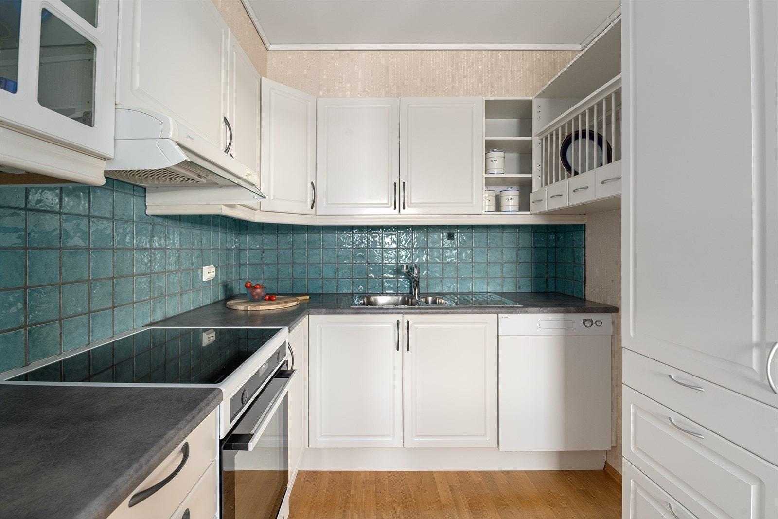 Kjøkken i lys utførelse med fliser over kjøkkenbenk. Galleribilde