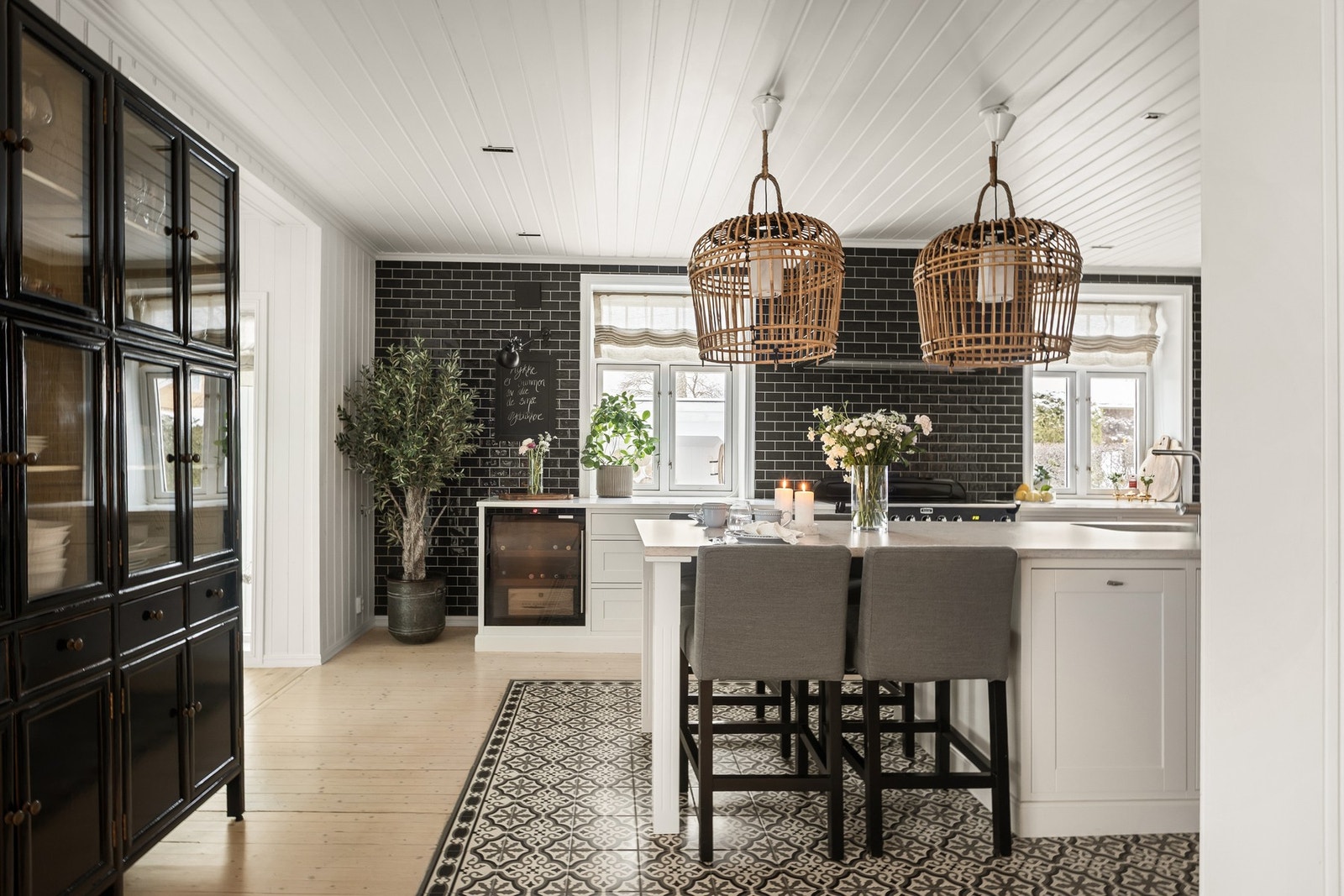 Mønstrede fliser lagt som et teppe under kjøkkenøy og spisegruppe Galleribilde