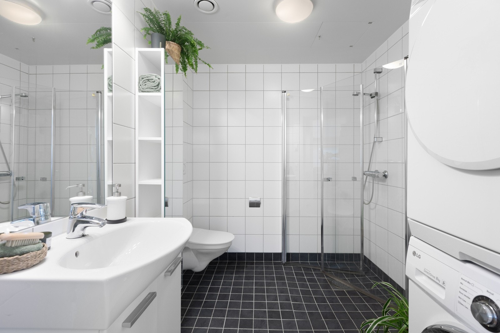 Badet er utstyrt med vegghengt toalett, dusjhjørne med svingbare glassdører og innredning med servant. Galleribilde