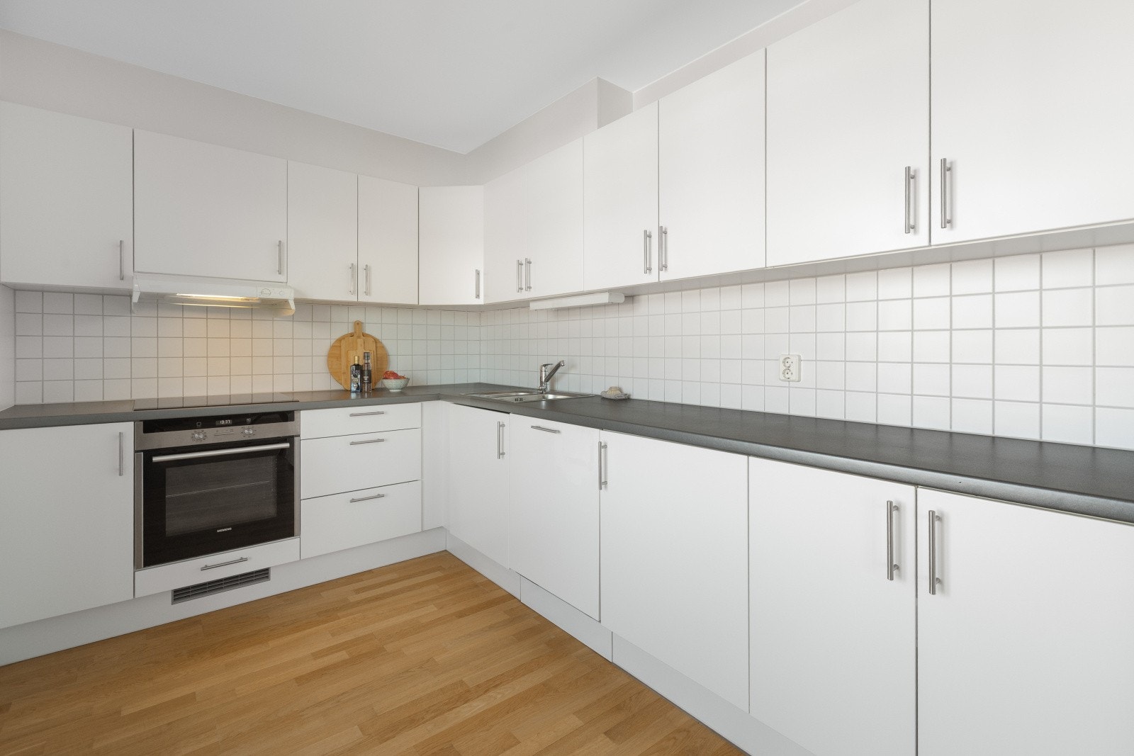 Kjøkkenet har en klassisk innredning med hvite glatte fronter og benkeplate av laminat. Det er flislagt mellom over- og underskapene. Galleribilde