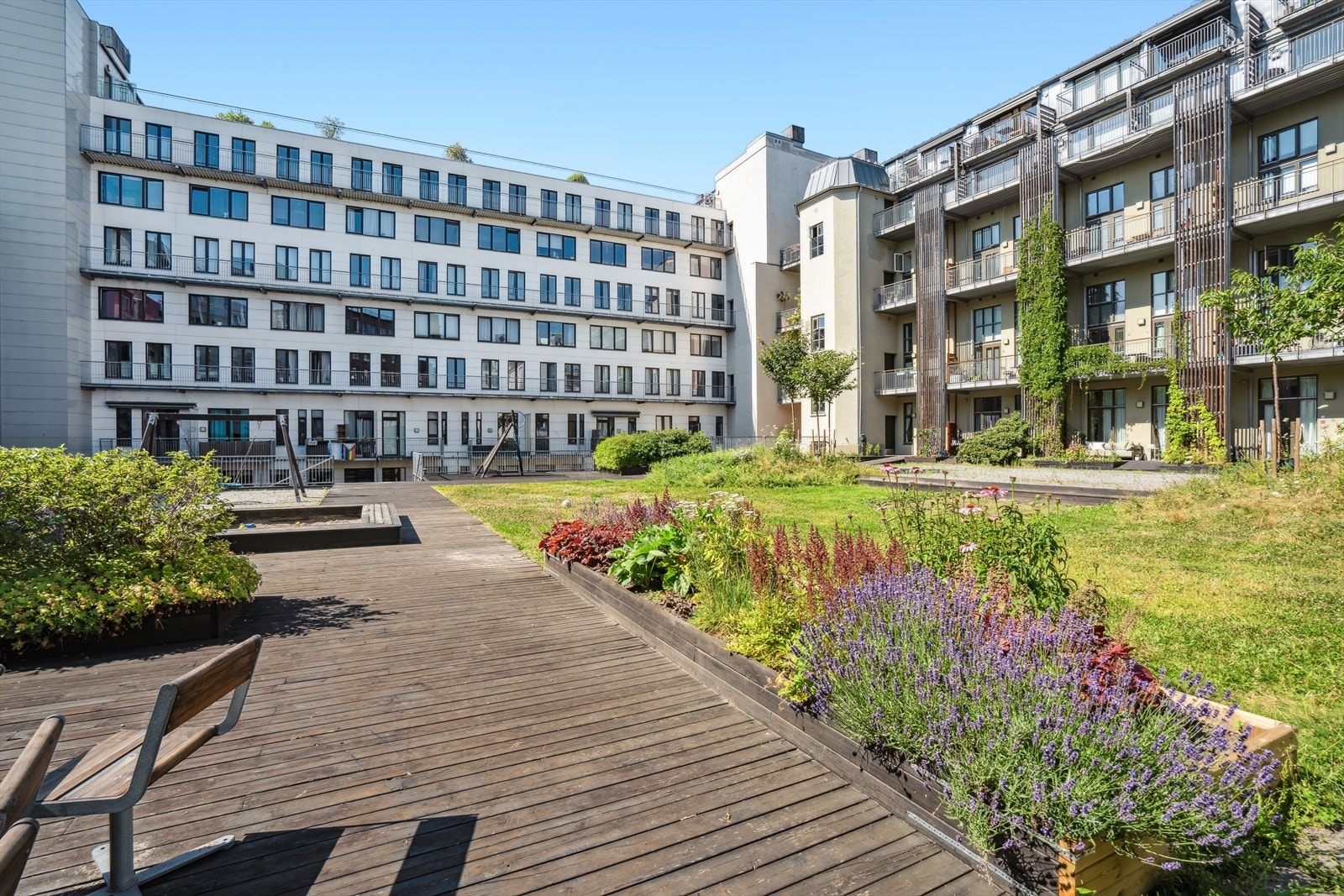 Urban bakgård som er meget pent opparbeidet med sitteplasser, plen og lekeplass. Galleribilde