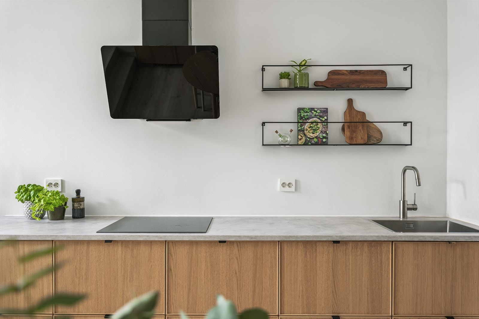 Delikat kjøkkeninnredning fra 2019 med slette fronter i lys eik, laminat benkeplate, enkel oppvaskkum og kjøkkenventilator med kanal ut. Galleribilde