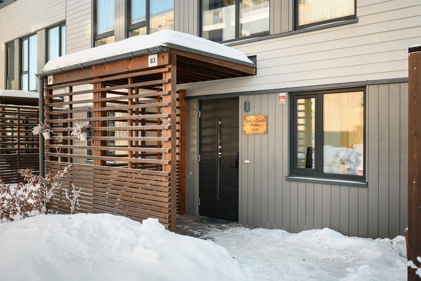 Boligen har et pent, overbygd inngangsparti med spilevegger og moderne utebelysning Galleribilde