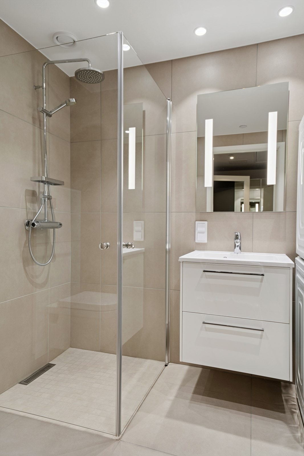 Vegghengt toalett, dusjvegger og servant med skuffer. Opplegg for vaskemaskin. Galleribilde