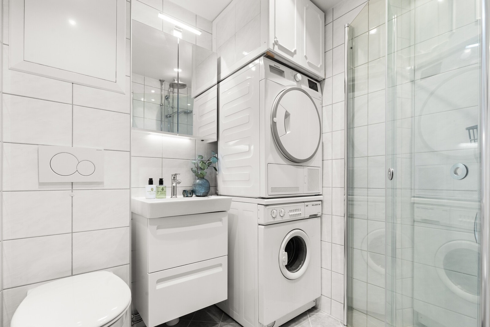 Flislagt bad med varmekabler. Servant, veggfestet klosett, dusj på gulv. tørketrommel og vaskemaskin følger leiligheten. Galleribilde