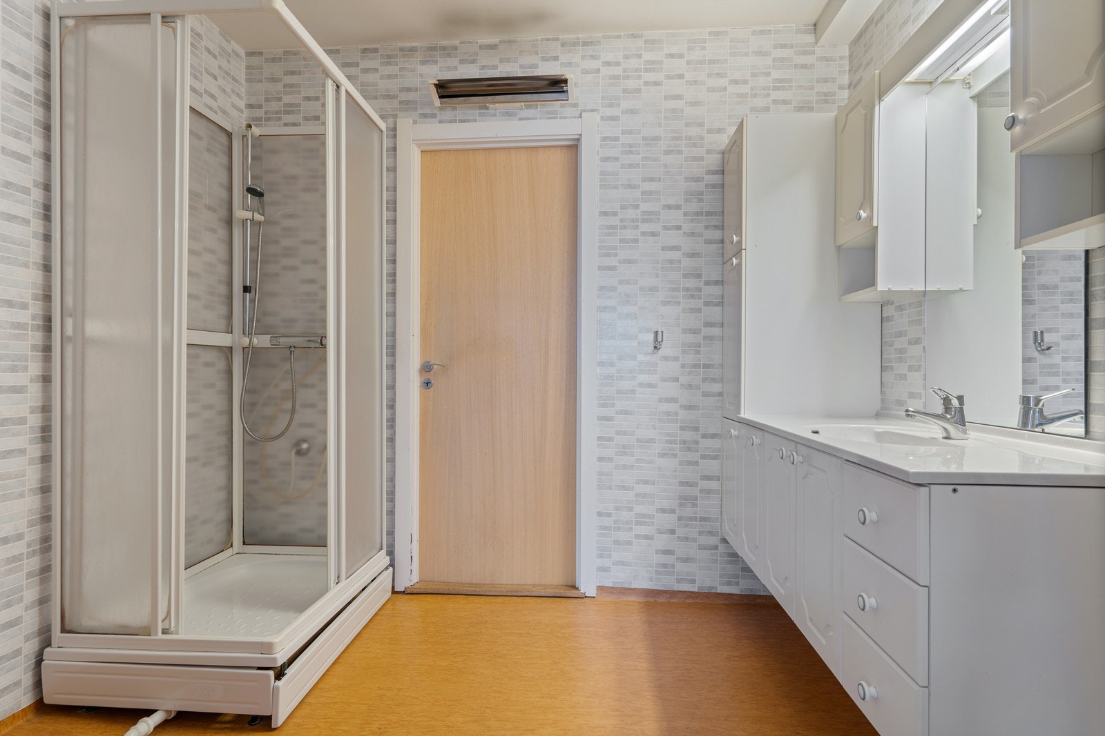 Baderom med servant med god skapplass, dusj og opplegg til vaskemaskin Galleribilde