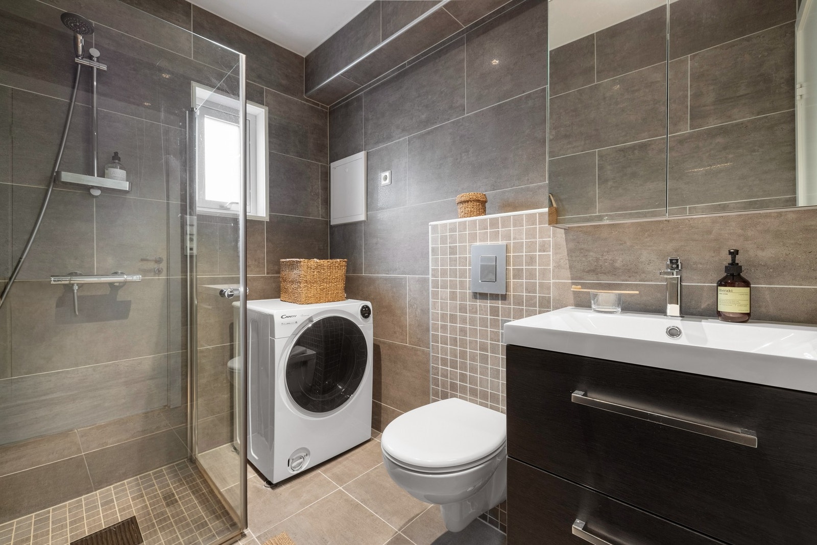 Badet er helfliset med mørke, delikate fliser og har underliggende varmekabler i gulv. Galleribilde