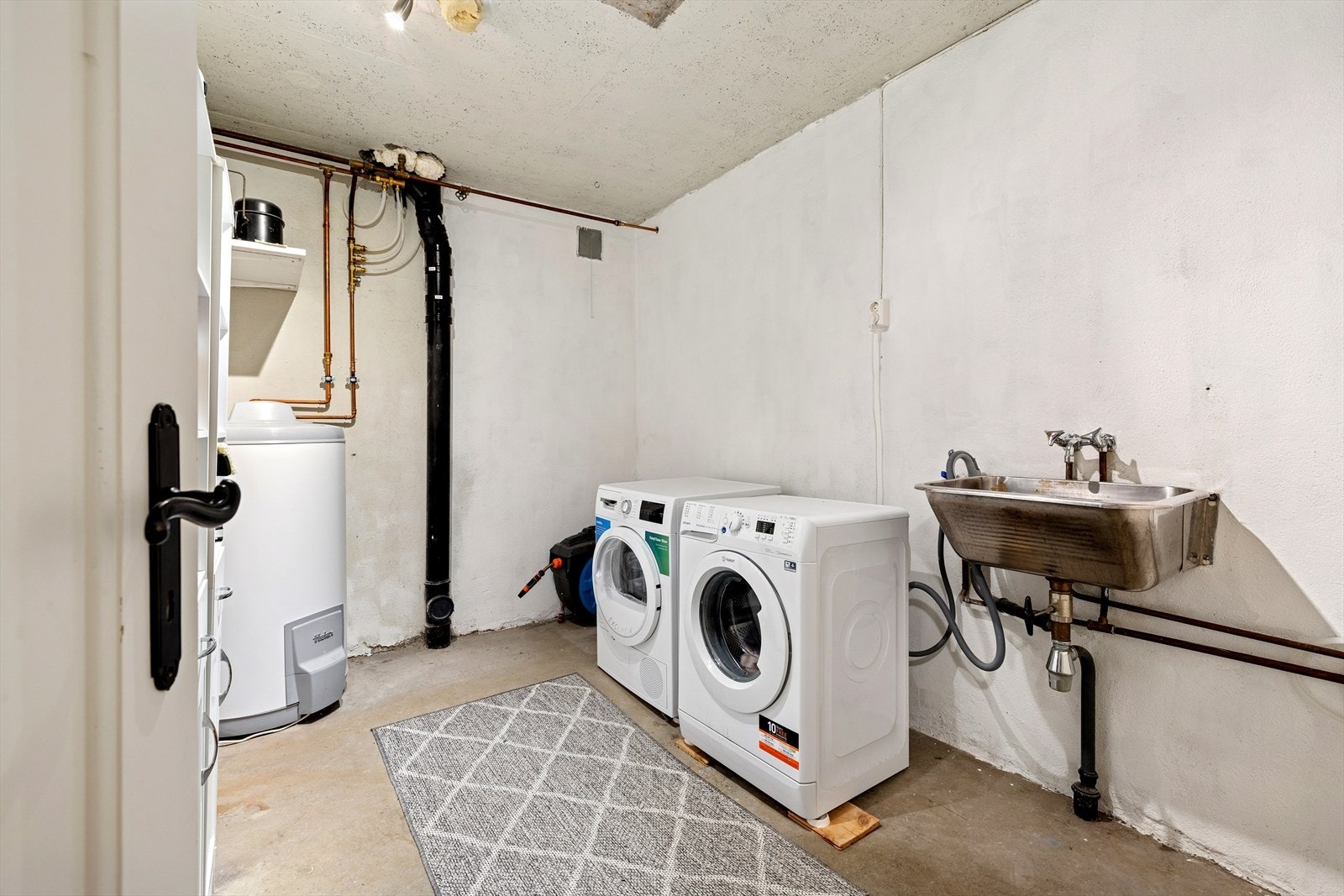 Enkelt vaskerom/teknisk rom med utslagsvask og opplegg for vaskemaskin. Galleribilde