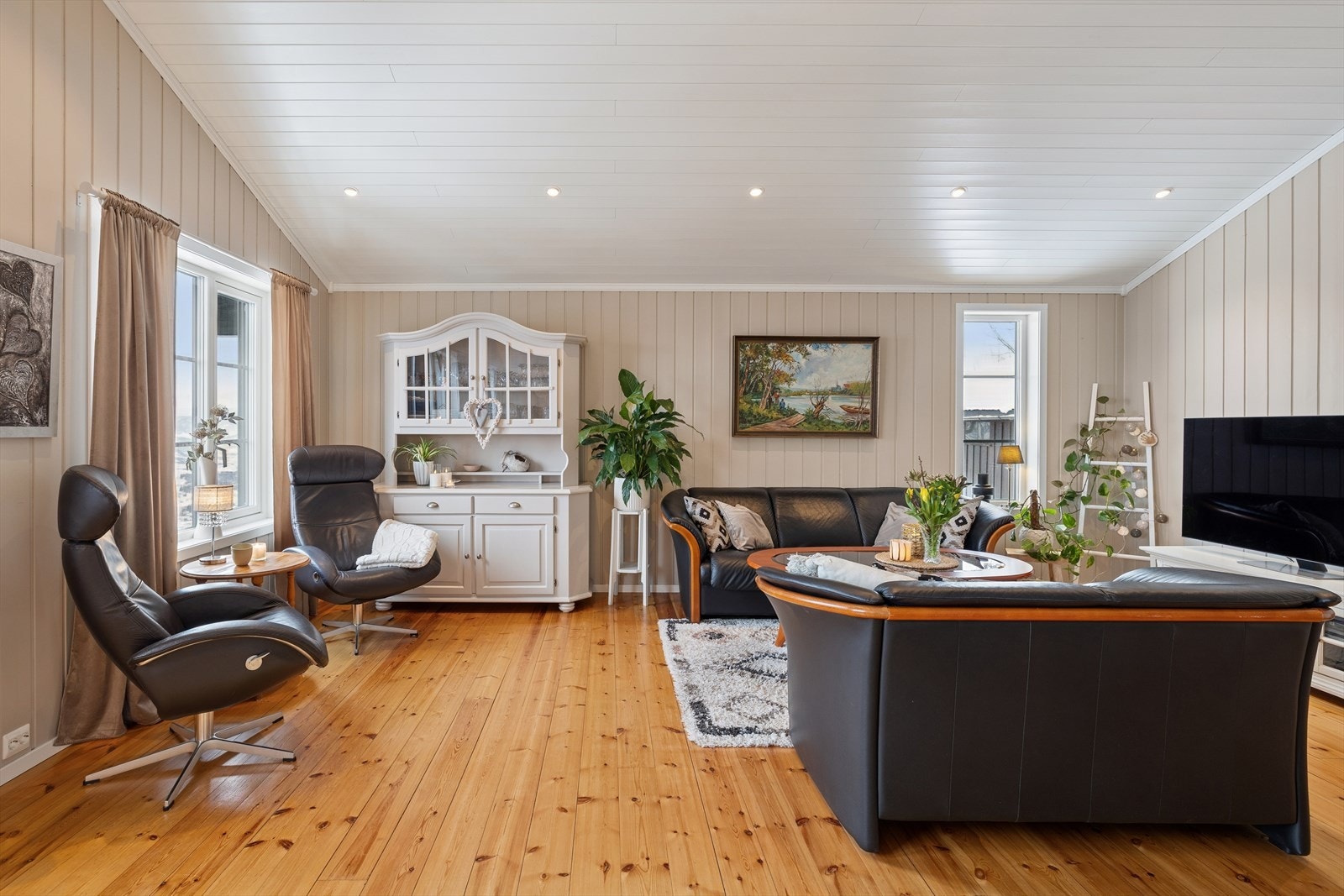 Innbydende stue med generøs takhøyde og store vindusflater som slipper inn rikelig med naturlig lys. Galleribilde