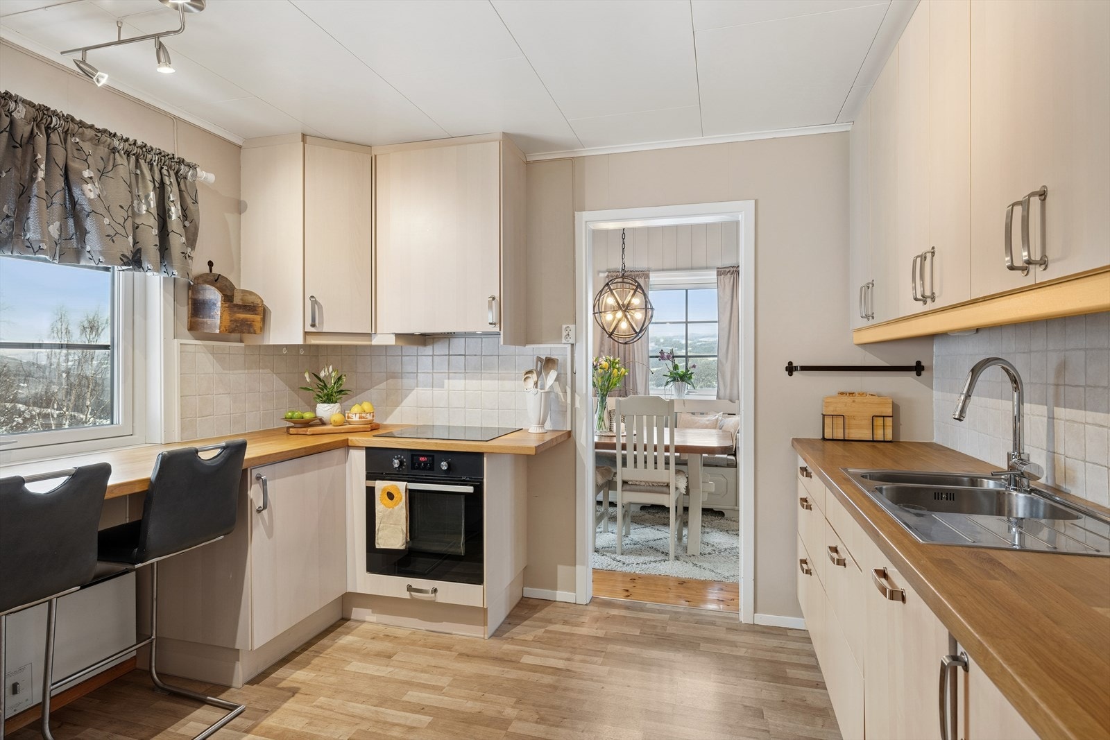 Delikat kjøkken fra 2013 med glatte fronter og heltre benkeplate med kjøkkenkum. Flislagt og belysning over benkeplate. Galleribilde