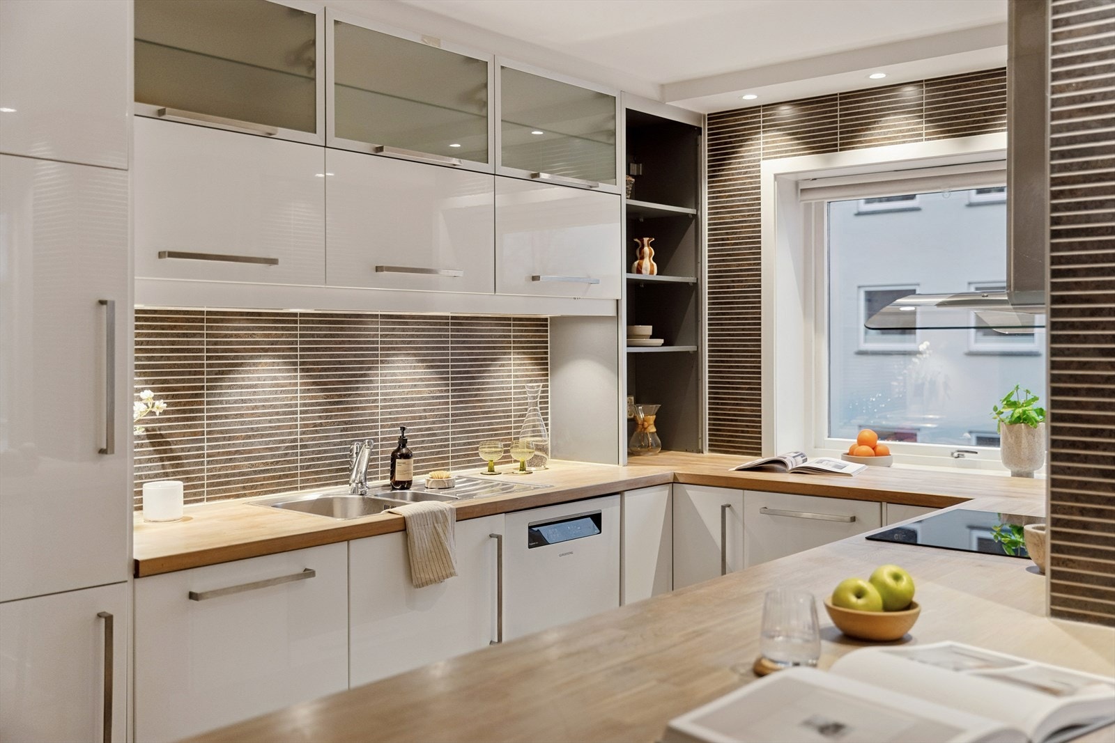 Kjøkkenet har en pen og funksjonell innredning fra Ikea, med trebenkeplate og hvite høyglansfronter som gir et moderne uttrykk. Galleribilde