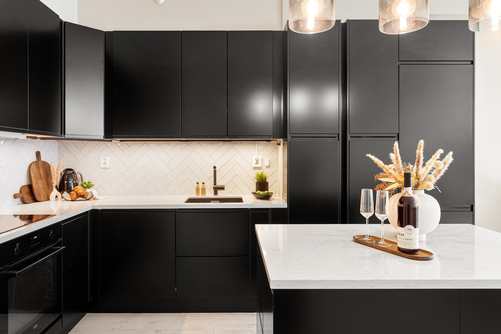 Kjøkkenet er innredet med glatte fronter i mørk utførelse, benkeplate i stein kompositt og oppvaskkum med ett-greps armatur. Galleribilde