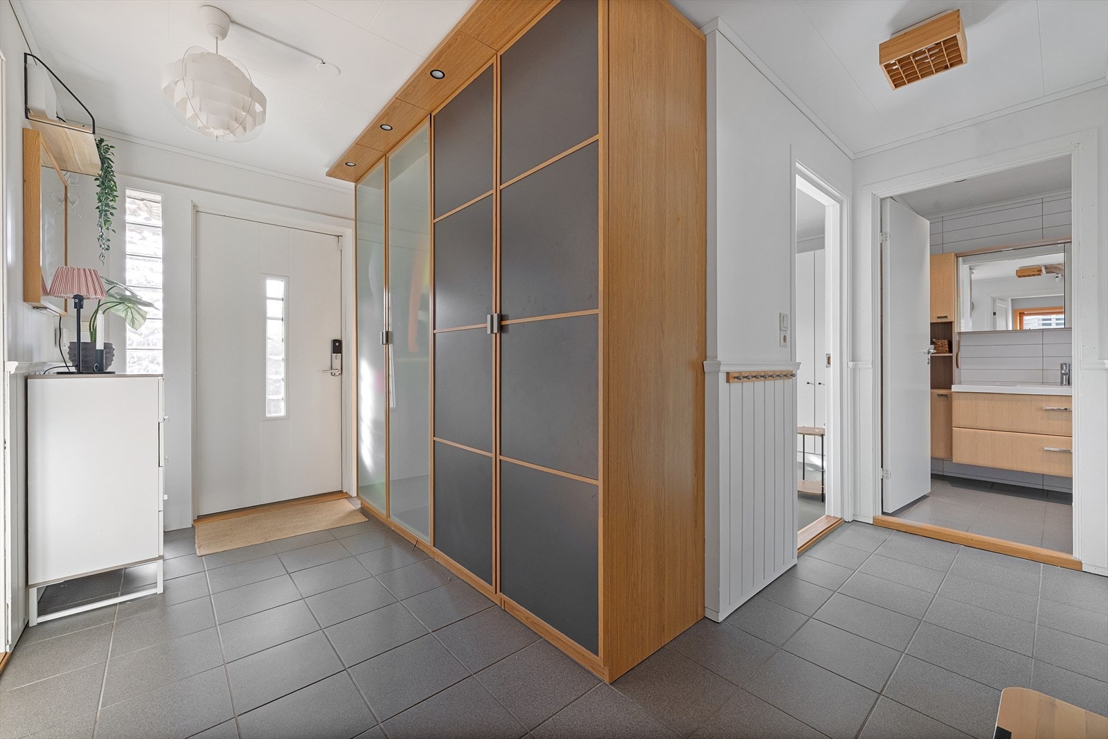 Romslig gang med stedstillpasset garderobeløsning og fliser på gulv Galleribilde