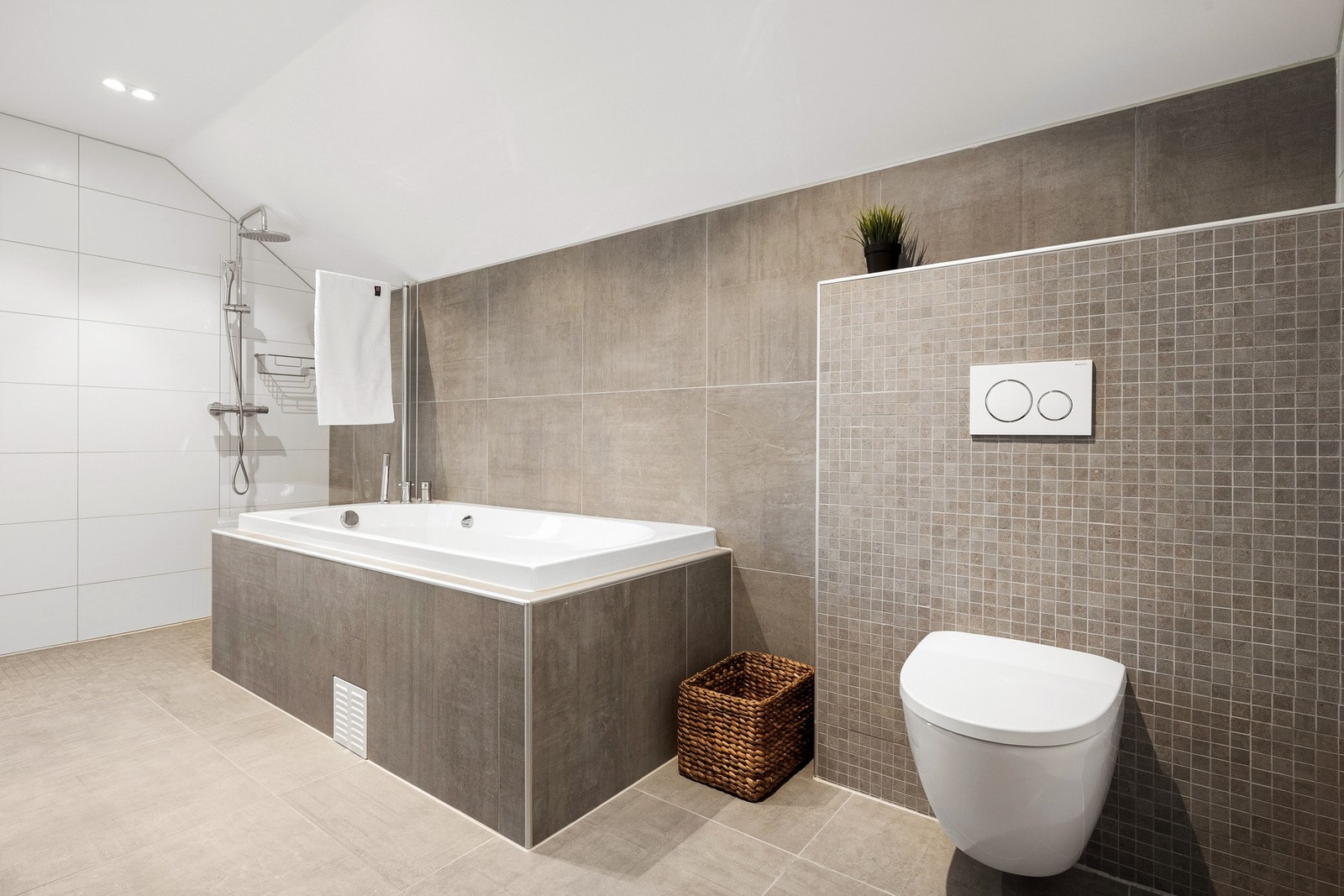 Det er innredet med vegghengt toalett, dusjhjørne med dusjgarnityr og vegg, badekar og baderomsmøblement med tilhørende høyskap, speil og belysning. Galleribilde