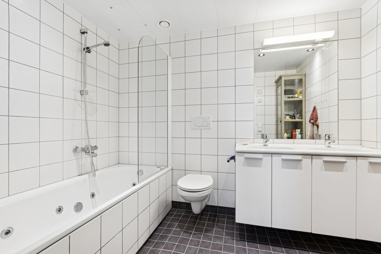 Badet er flislagt med elektriske varmekabler i gulv. Det er innredet med boblebadekar, dobbel servant i servantskap og vegghengt toalett. Galleribilde