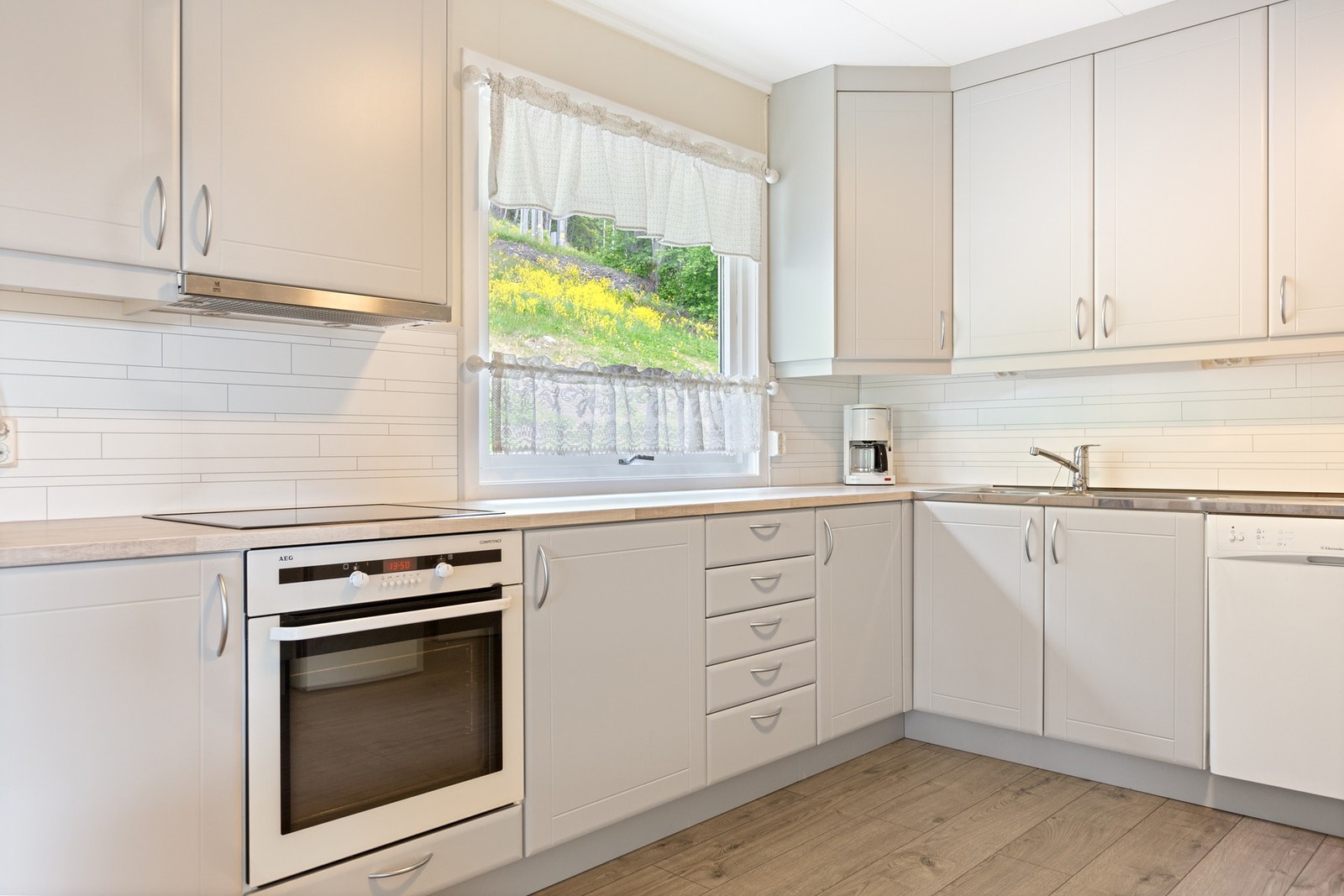 Integrerte hvitevarer som komfyr, koketopp og ventilator. Frittstående oppvaskmaskin og kjøl-/fryseskap. Galleribilde