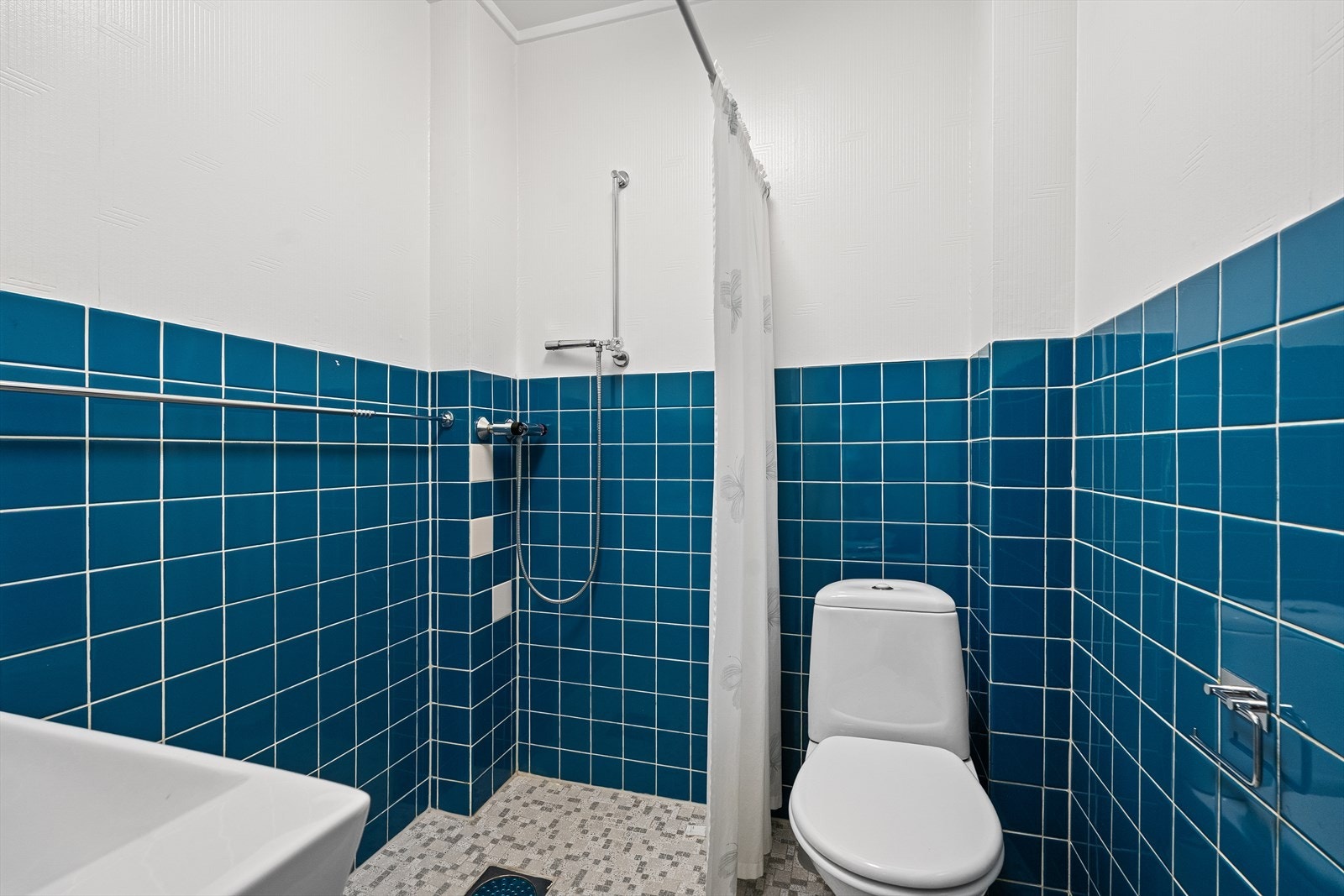 Flislagt baderom med dusj og toalett. Galleribilde