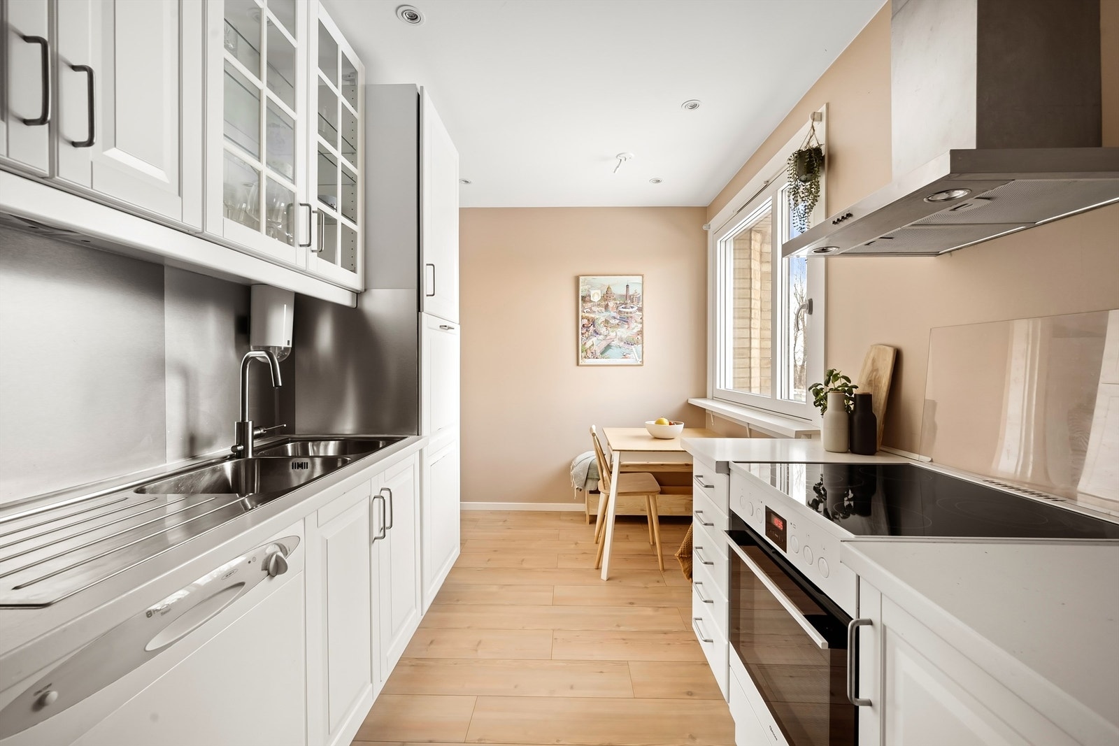 Kjøkkeninnredning med hvite, profilerte fronter og en laminat benkeplate med nedfelt vaskekum. Galleribilde