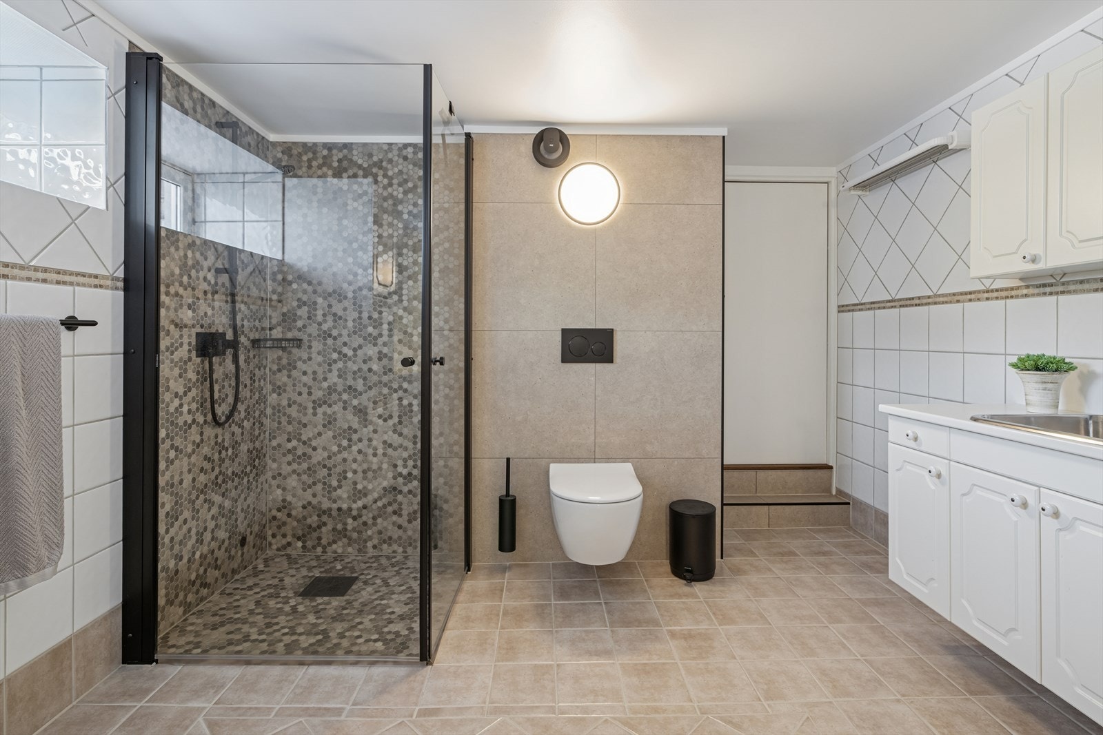 Separat toalettsone og en romslig dusj med mosaikkfliser. Galleribilde