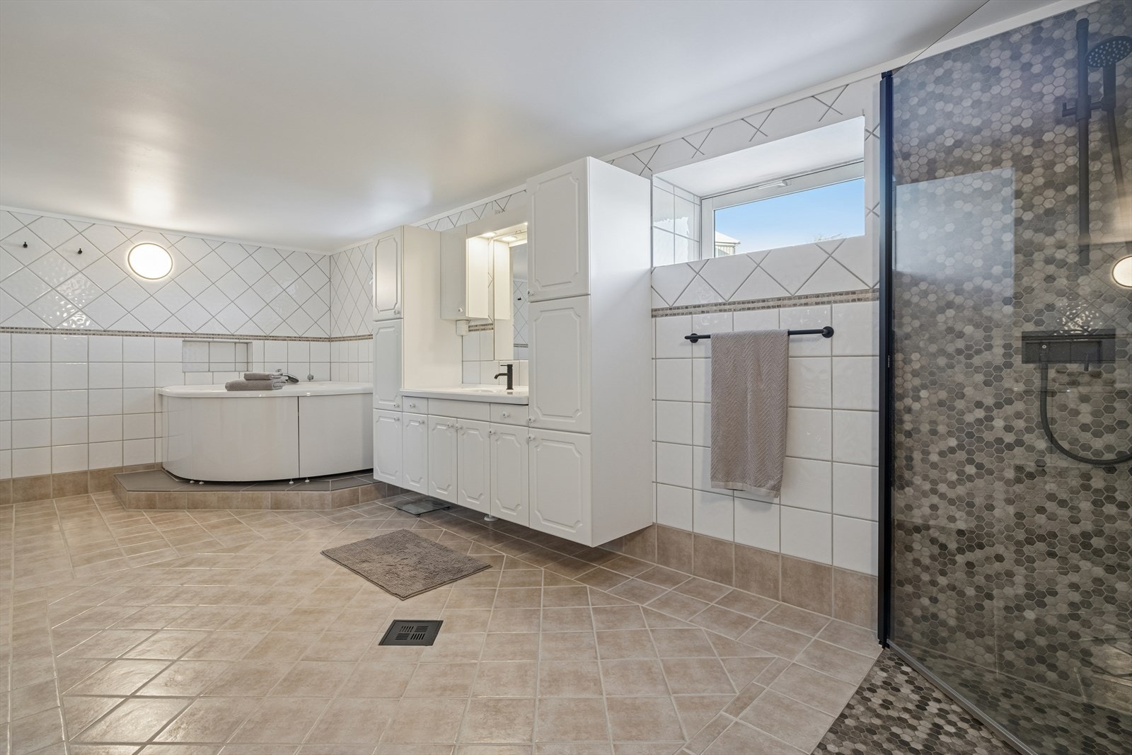 Rommet har dusjnisje (oppgradert med nye fliser og membran i 2024) og hjørnebadekar, baderomsinnredning og vegghengt toalett. Galleribilde