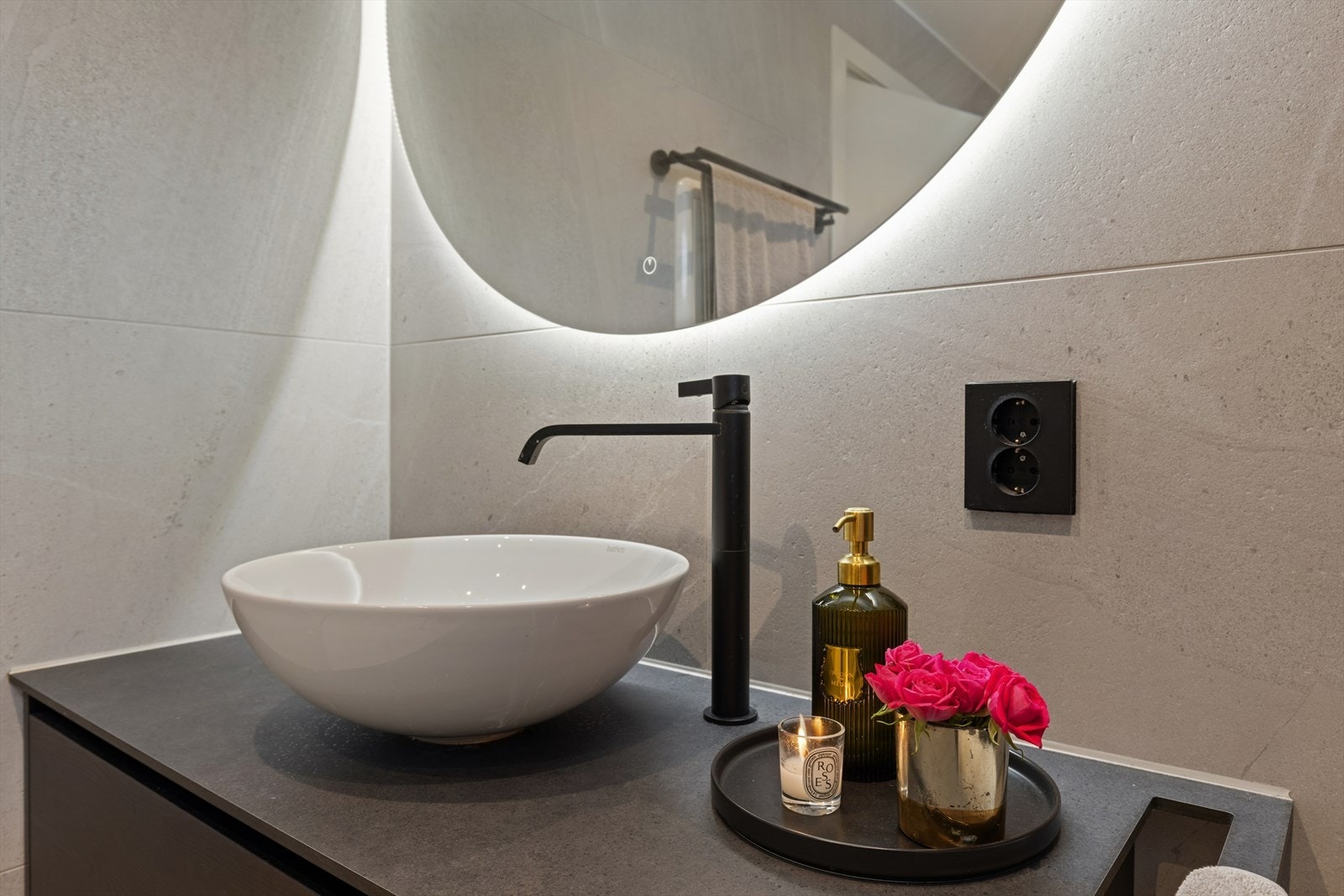 Baderommet har et moderne speil med integrert belysning som gir et jevnt og behagelig lys. Under speilet ligger en elegant og praktisk vask med god benkeplass. Galleribilde