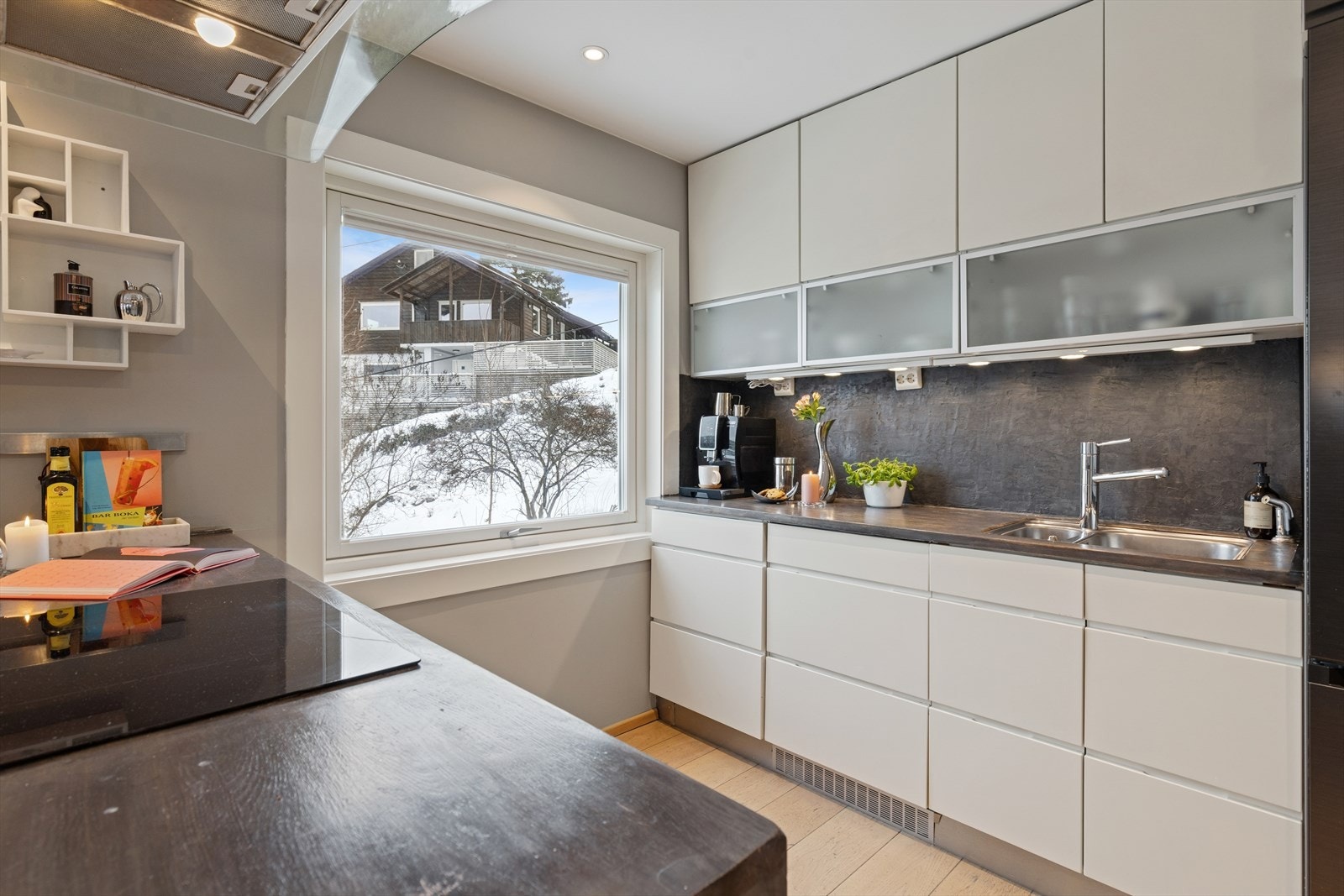 Belysningen er nøye planlagt med spotter under overskap som gir en jevn og behagelig arbeidsflate, mens spotter i taket tilfører både funksjonelt lys og en lun stemning. Galleribilde