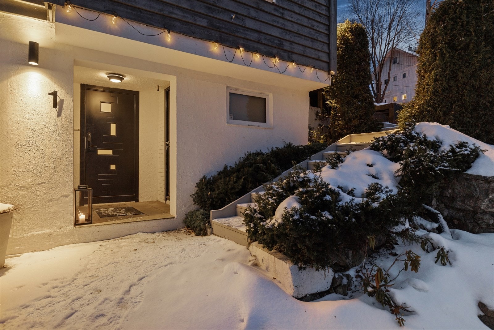Når kvelden senker seg, trer inngangspartiet virkelig fram som et varmt og velkomment blikkfang. Fin belysningen skaper en lun og behagelig atmosfære som både ønsker gjester velkommen og gir hjemmet godt førsteinntrykk. Galleribilde