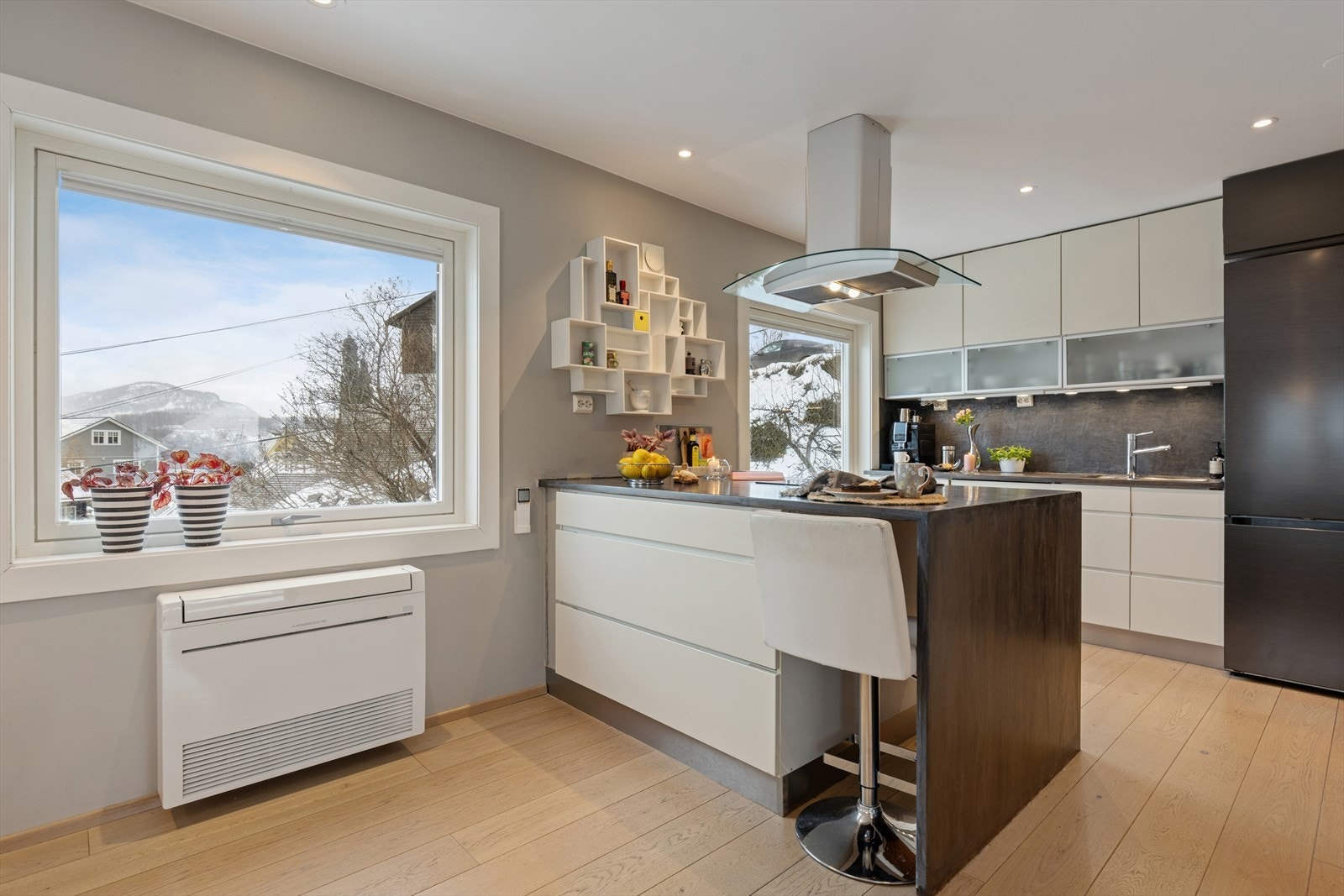 Kjøkkenet fremstår moderne og svært innbydende, med rene linjer og tidløst design. De glatte frontene kombinert med en flott heltre benkeplate gir rommet et elegant uttrykk, samtidig som materialene oppleves både solide og praktiske i hverdagen. Galleribilde