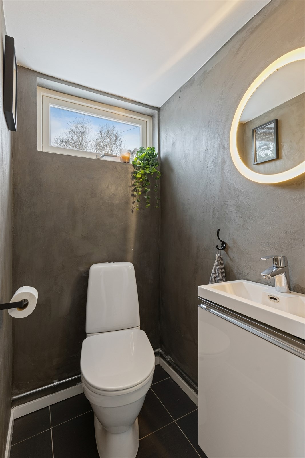 Her finner du også et praktisk toalettrom, ideelt plassert for både beboere og gjester. Fliser på gulv, varmekabler, toalett og servant med underskap. Galleribilde