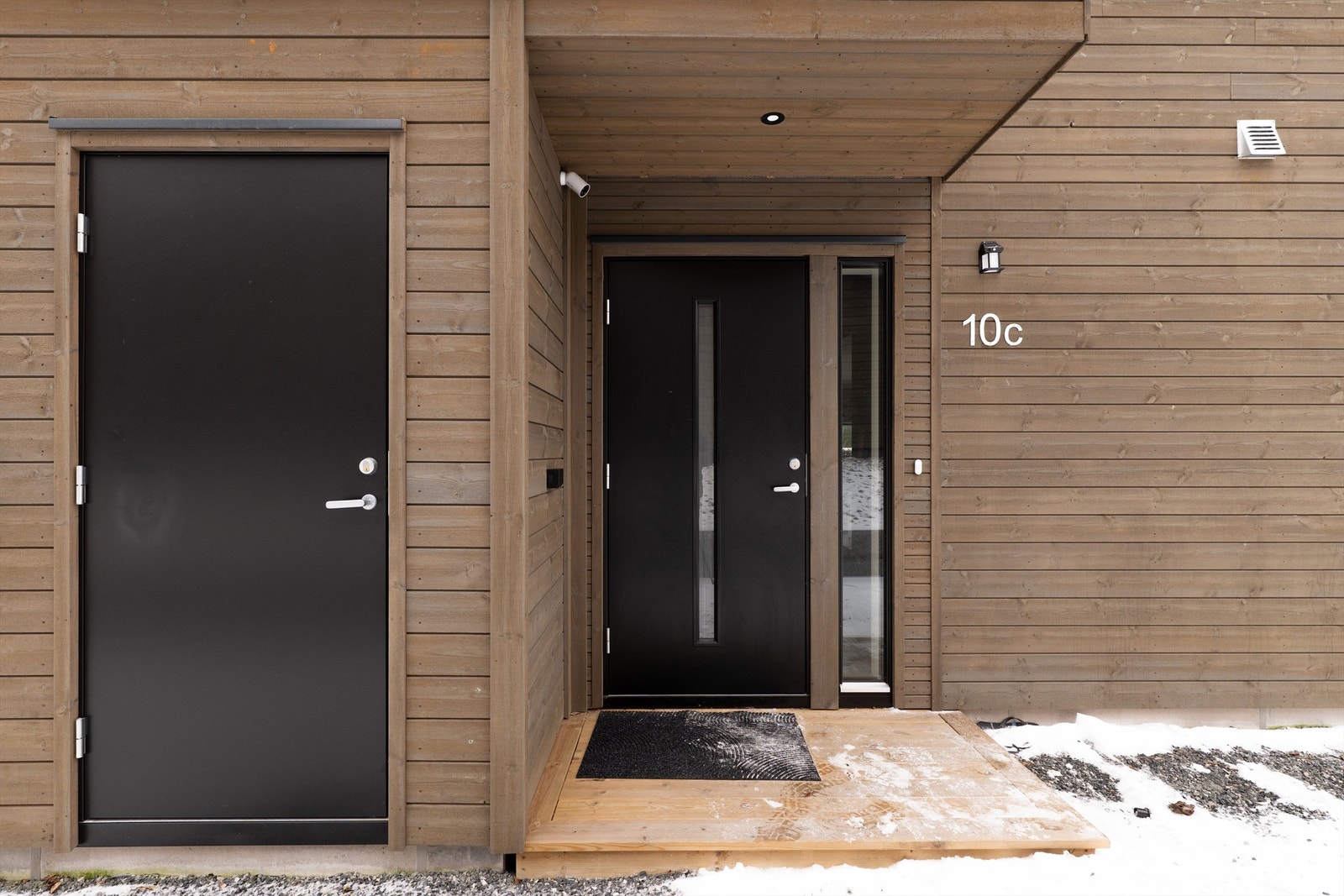 Overbygg med innfelt spot skjermer inngangspartiet godt mot nedbør. Fra inngangspartiet er også sportsbodens lagringsplass lett tilgjengelig. Galleribilde