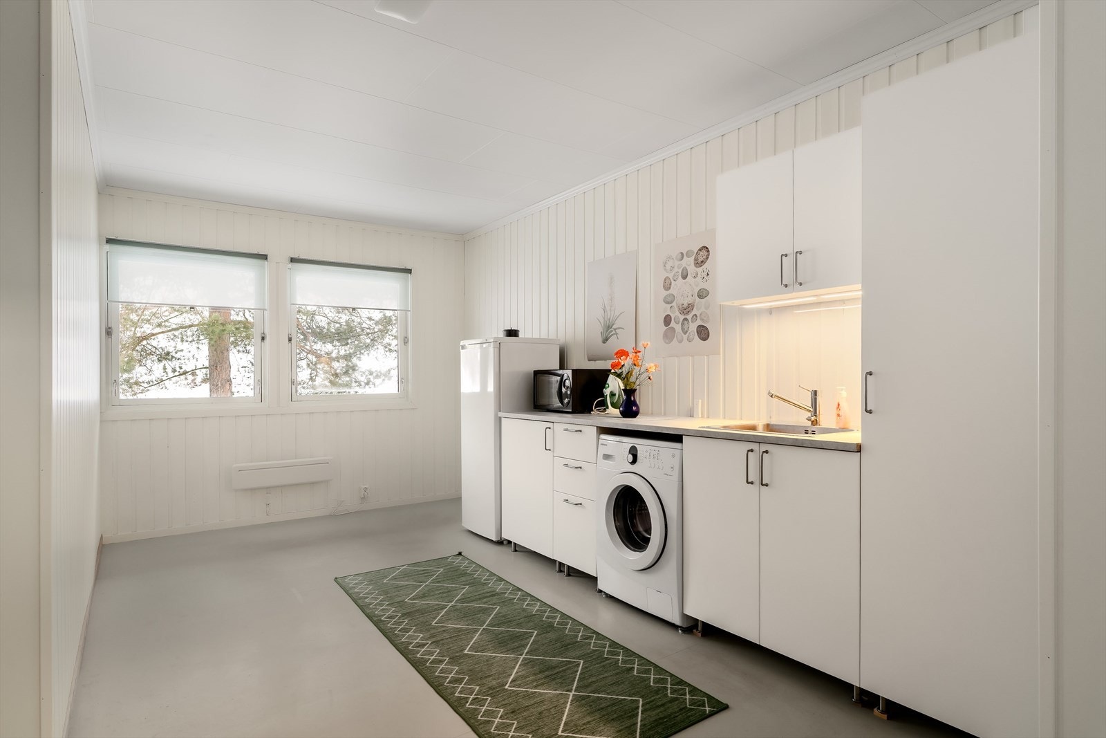 Det ene rommet er innredet som et vaskerom med god gulvplass og funksjonell innredning. Rommet er tilrettelagt for vaskemaskin og øvrige hvitevarer, med benkeplass og oppbevaringsmuligheter. Galleribilde