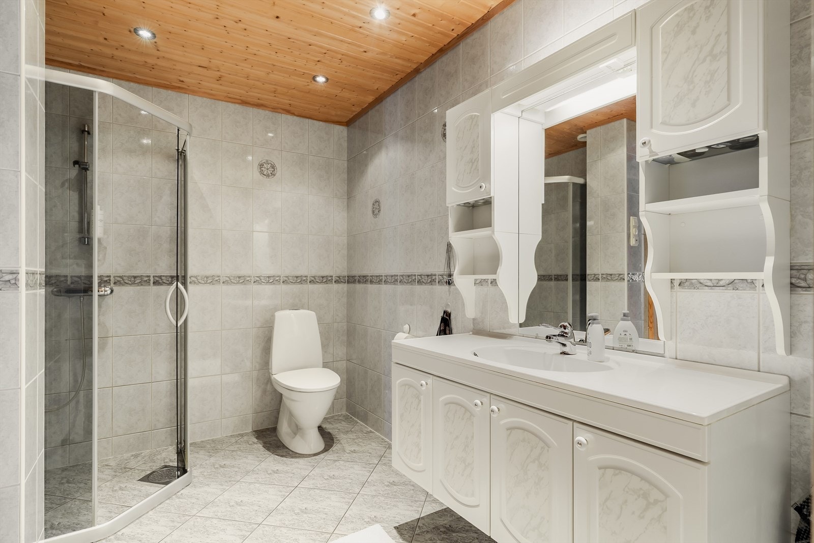 Badet fremstår som romslig og funksjonelt, med flislagte gulv og vegger i lyse, nøytrale toner. Galleribilde