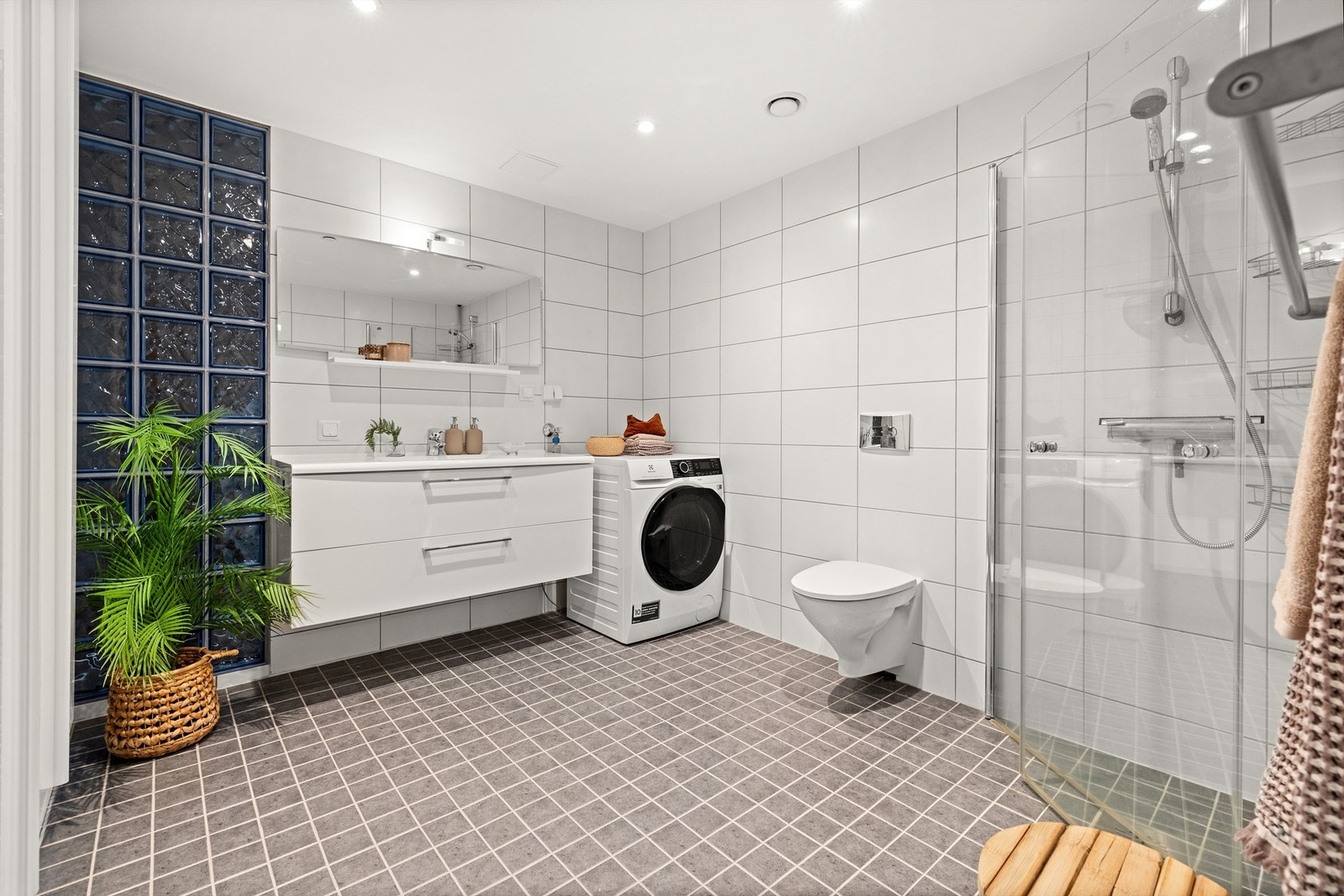 Hovedbadet er romslig med flislagt gulv, dusjhjørne og opplegg for vaskemaskin. Galleribilde