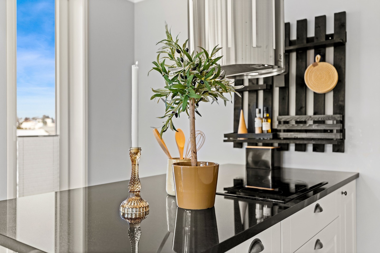 Kokeplaten er praktisk integrert i kjøkkenøya, med en fritthengende ventilator over. Galleribilde