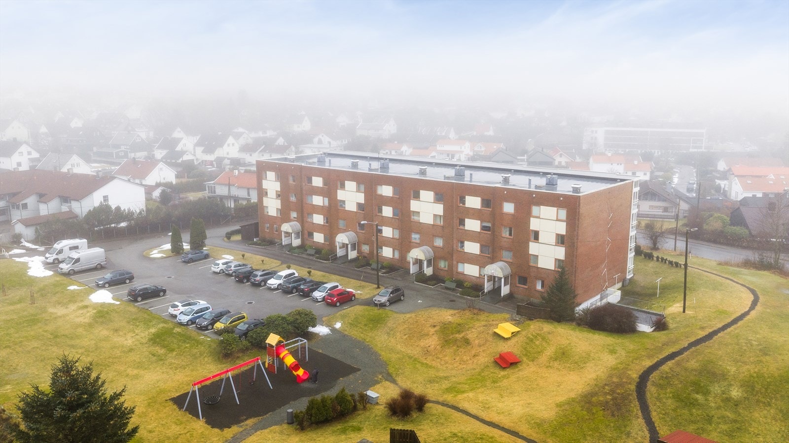 Pent opparbeidet fellestomt med asfalterte parkeringsplasser og rikelig med grøntareal/gressplener. Galleribilde