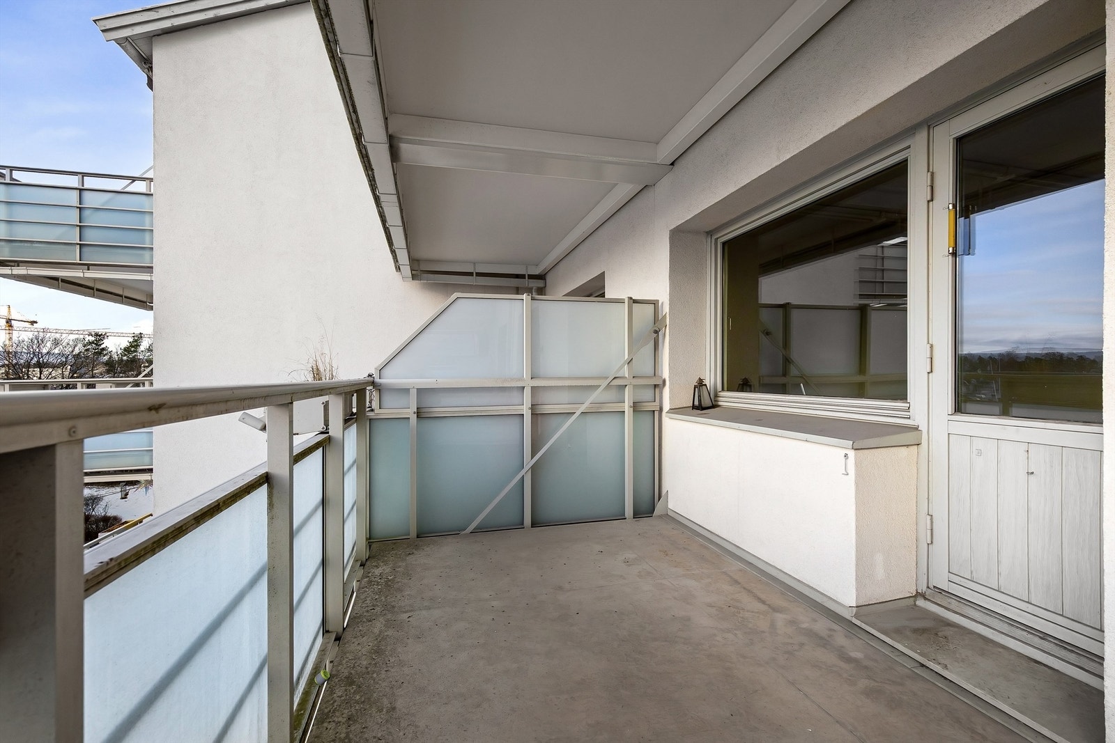 Balkongen har betonggulv og rekkverk i stål og frostet glass. Galleribilde