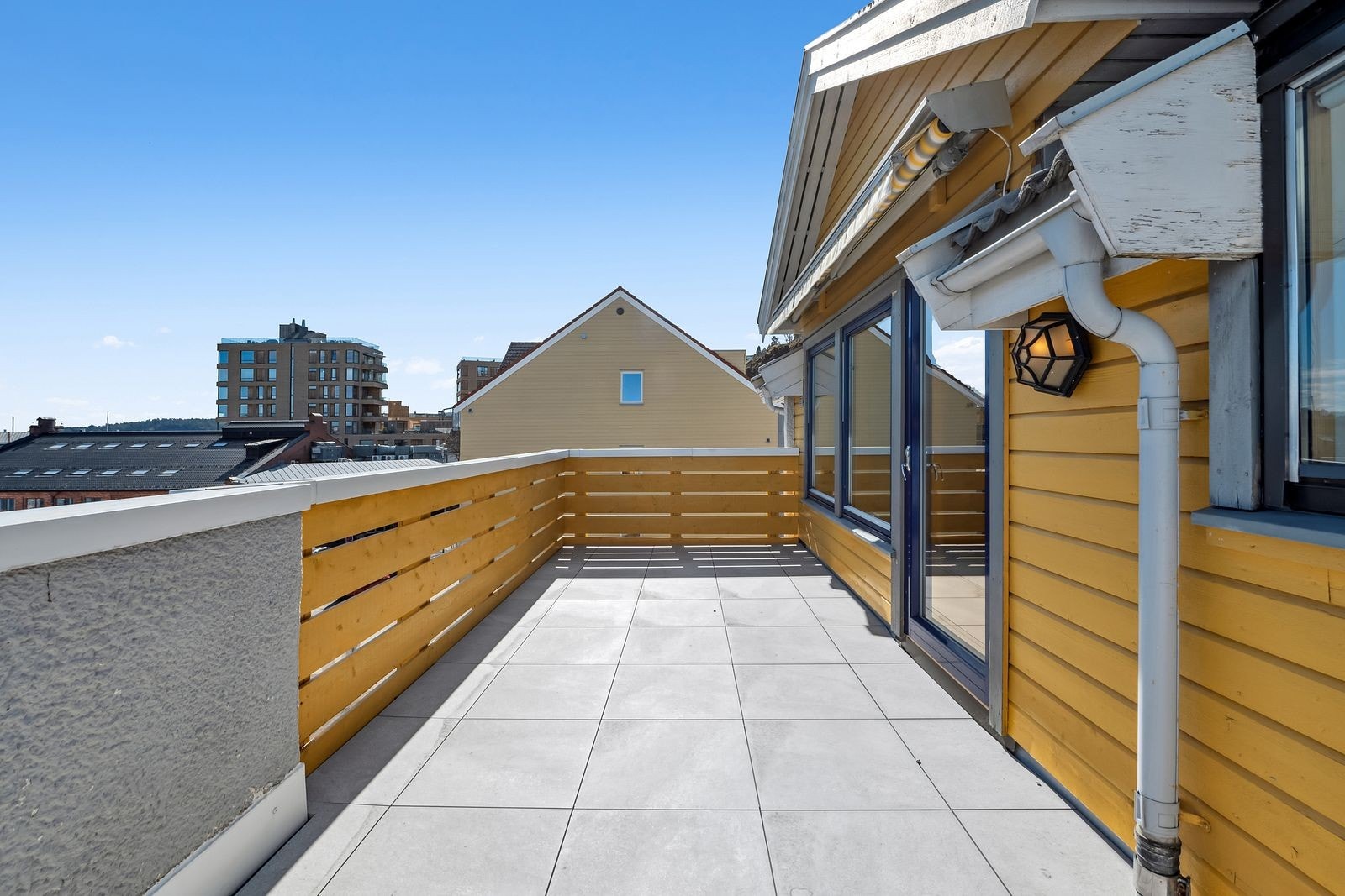 Sommerbilde av terrassen tatt i 2025. Det er installert varmepumpe etter bildet er tatt. Galleribilde