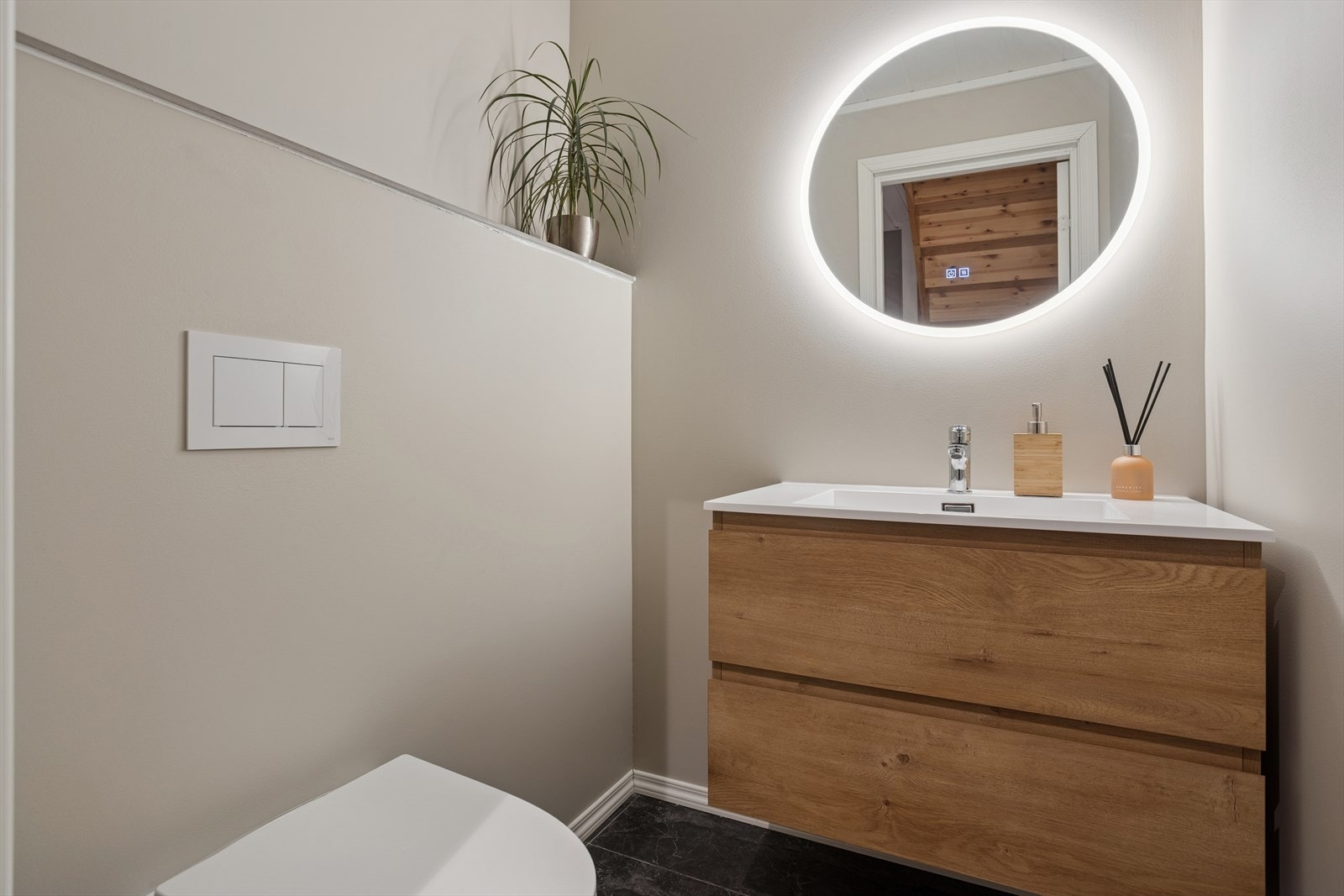 Toalettrom med vegghengt toalett, servant med innredning, speil med belysning og "touch"-panel. Galleribilde