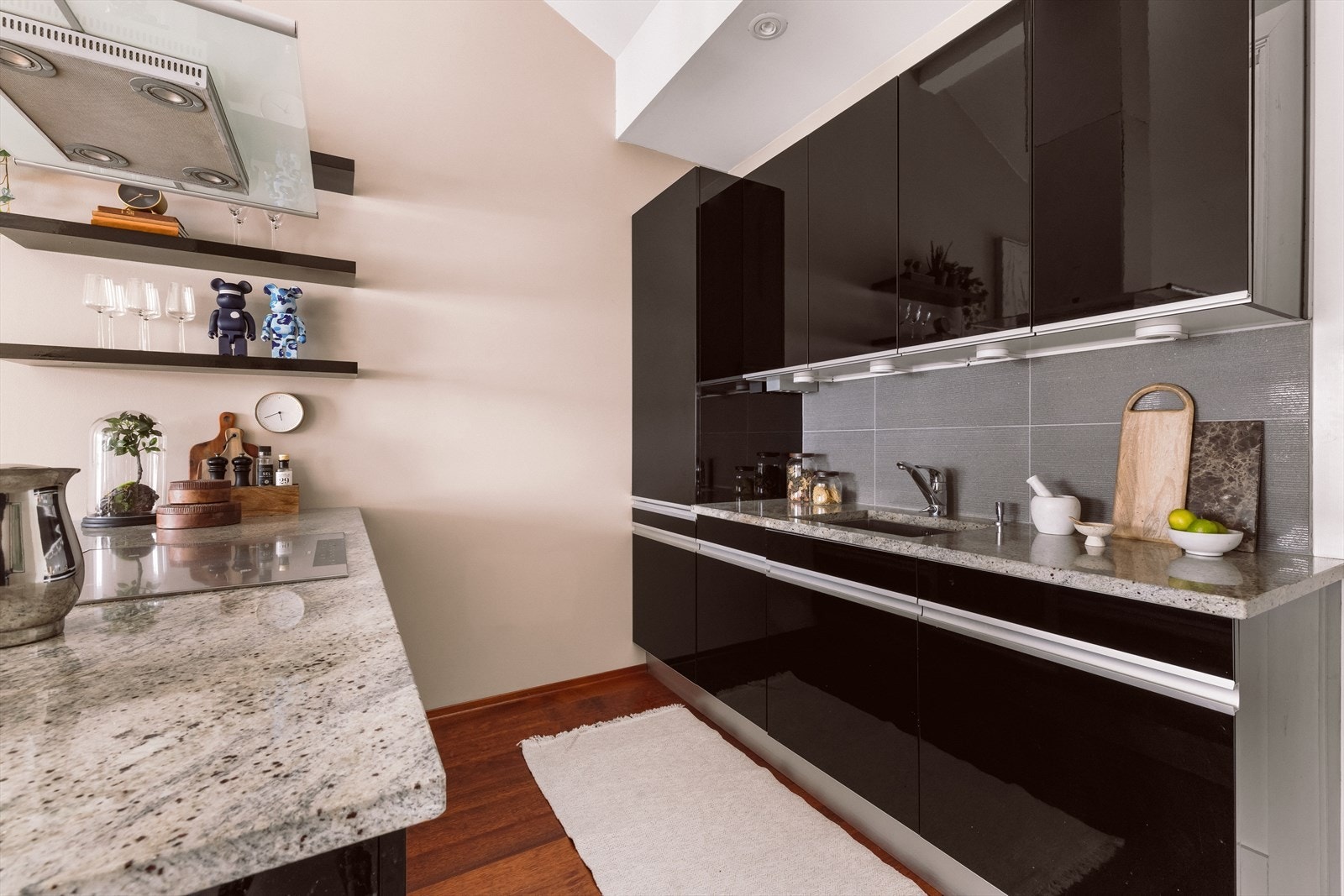 Lekker innredning som består av mørke, glatte fronter, fliser mellom over- og underskap og en lekker benkeplate i stein. Galleribilde