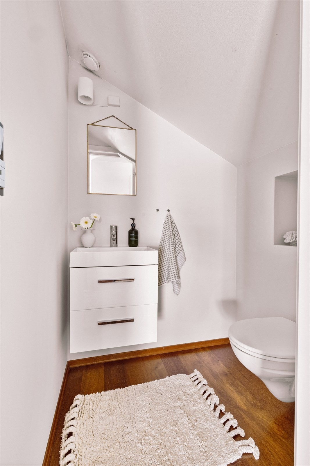 Separat toalettrom med vegghengt toalett, speil og nedfelt servant med underskap. Galleribilde