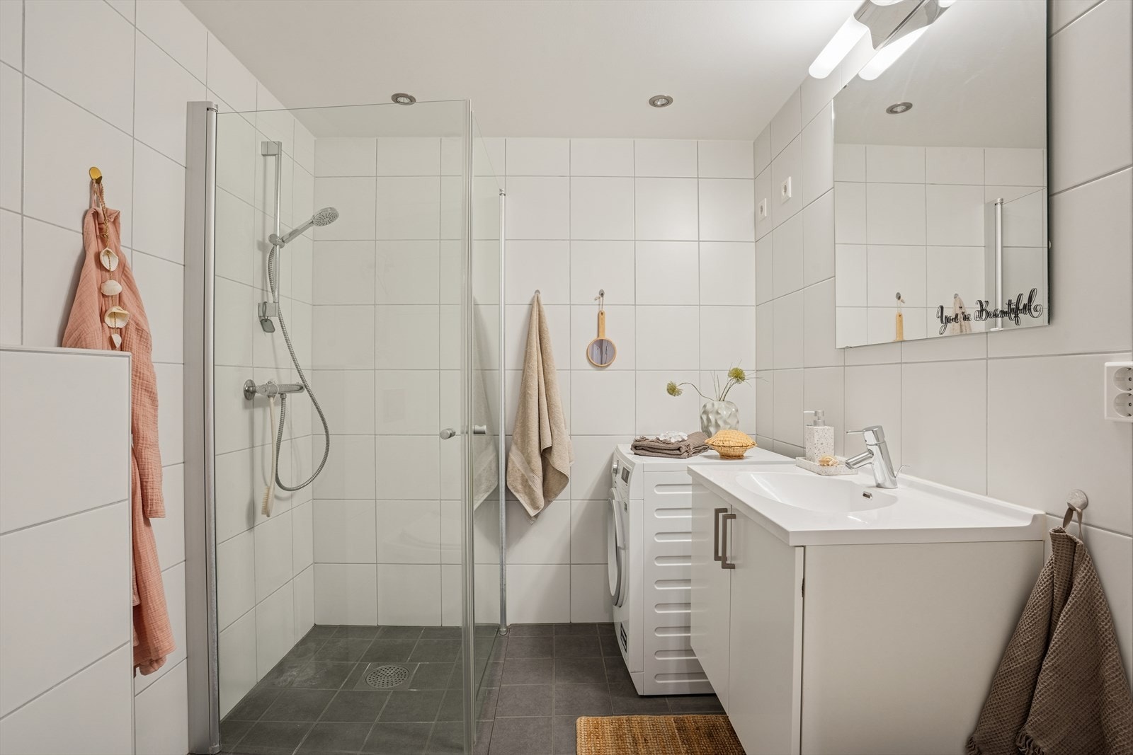 Lyst og romslig bad med fliser på både vegger og gulv, og med opplegg for vaskemaskin. Galleribilde