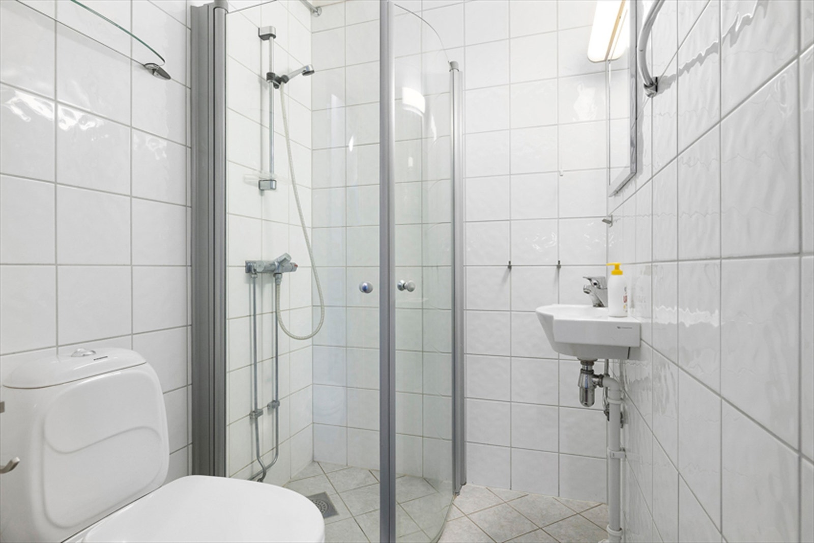 Flislagt bad med toalett, servant og dusj. Galleribilde