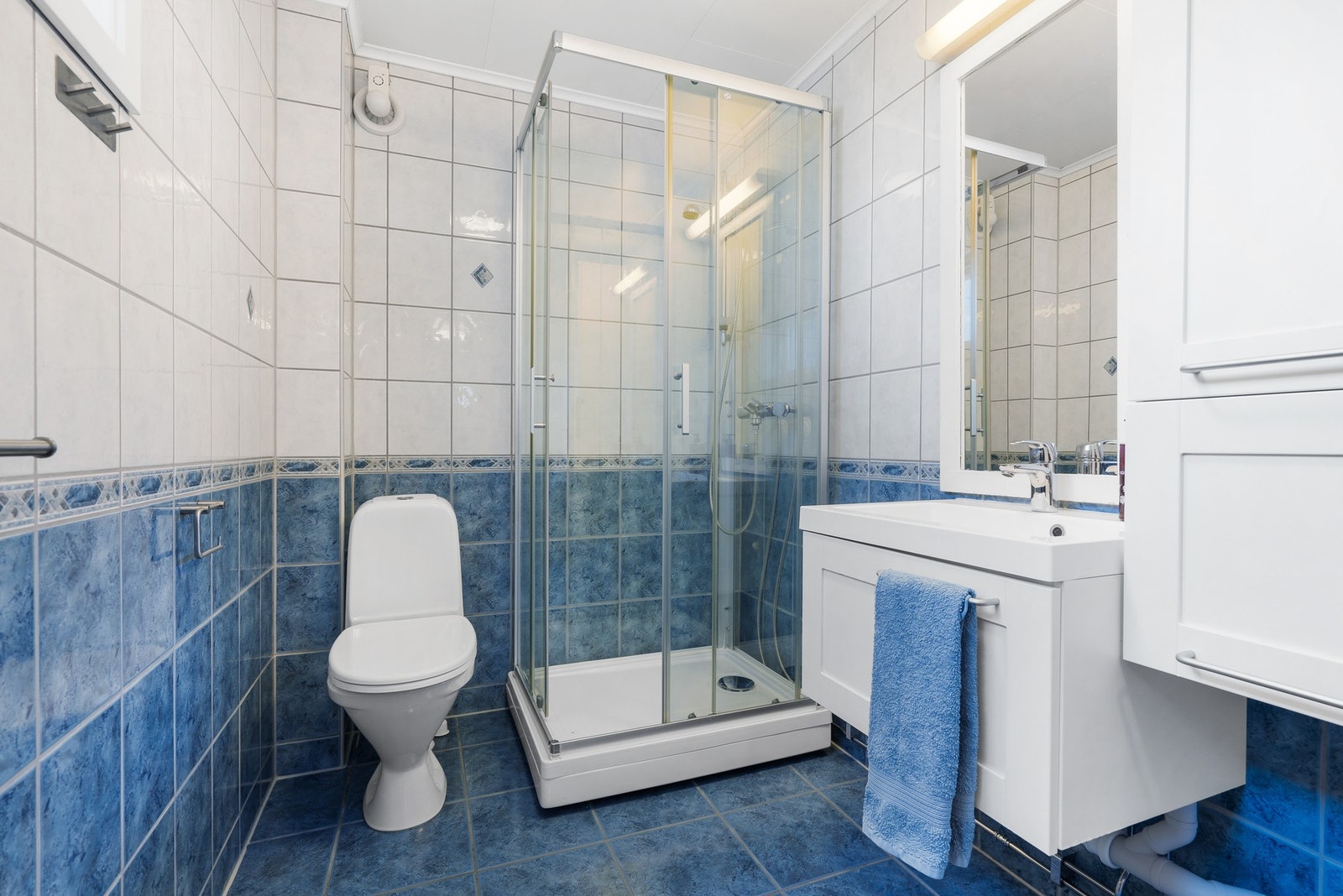 HYBEL - Romslig og flislagt bad med varme i gulv. Toalett, dusjkabinett og servantinnredning med speil og høyskap. Galleribilde