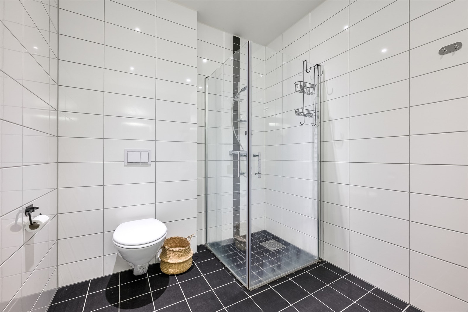 Badet er utstyrt med vegghengt toalett og dusjhjørne med praktiske, innfellbare dører. Galleribilde