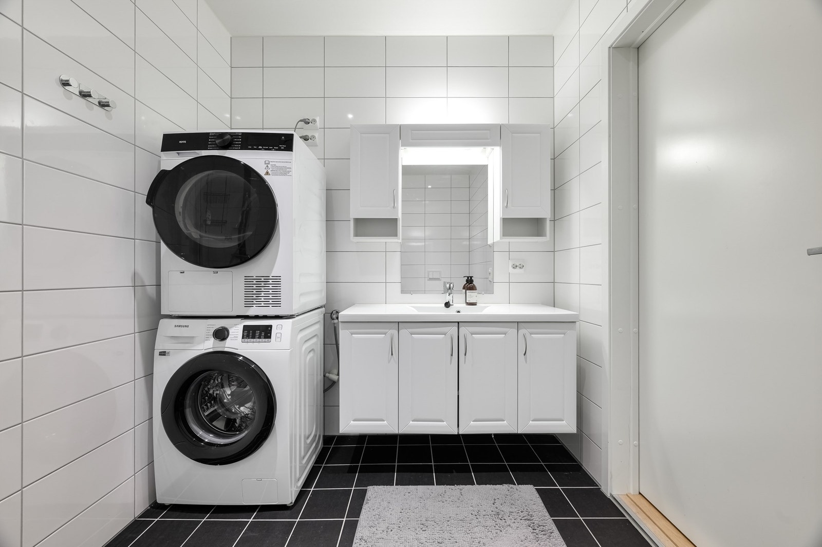 Moderne, flislagt bad med vegghengt servantinnredning og opplegg for vaskemaskin. Galleribilde